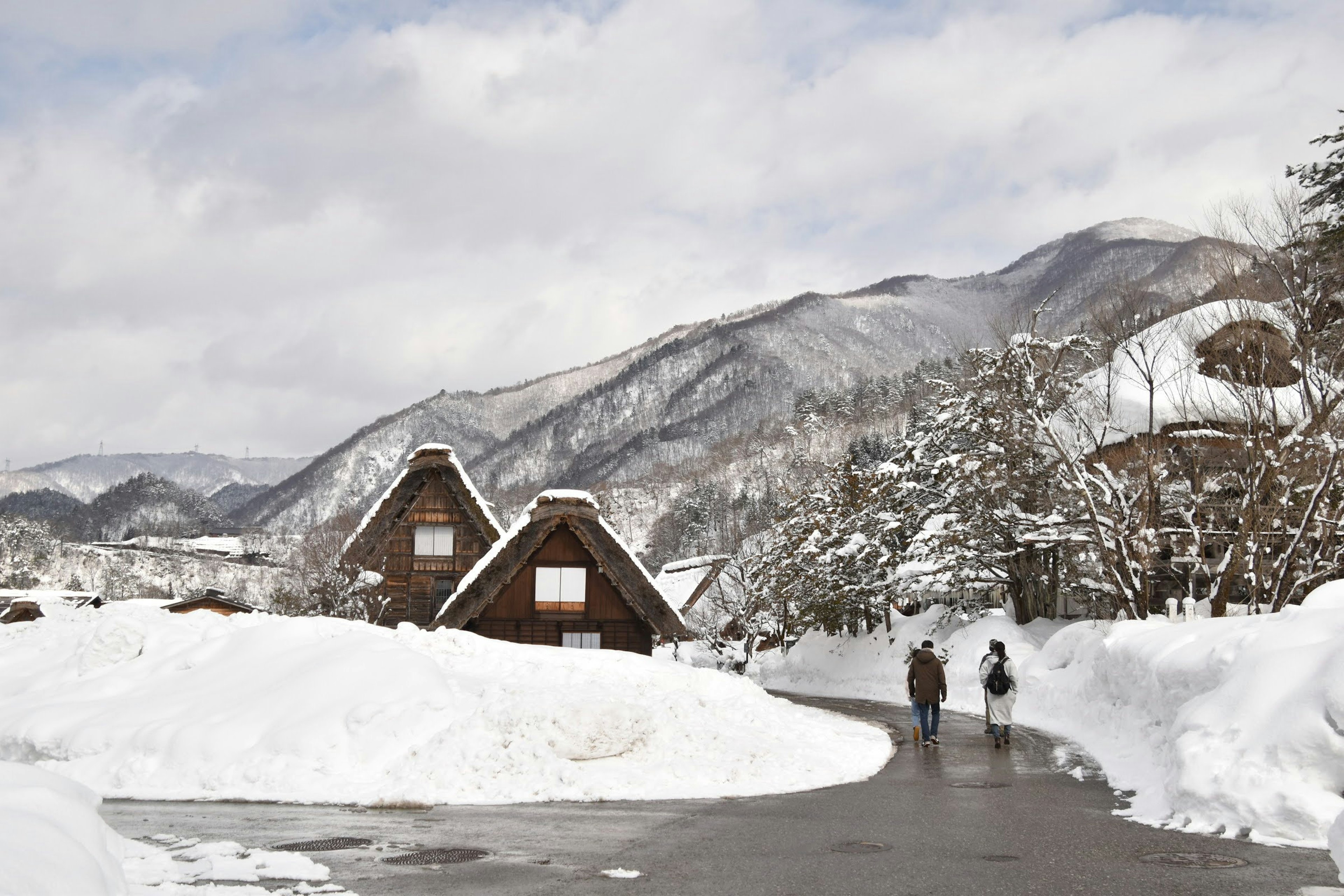 雪覆盖的村庄和背景山脉的风景，行人正在走动