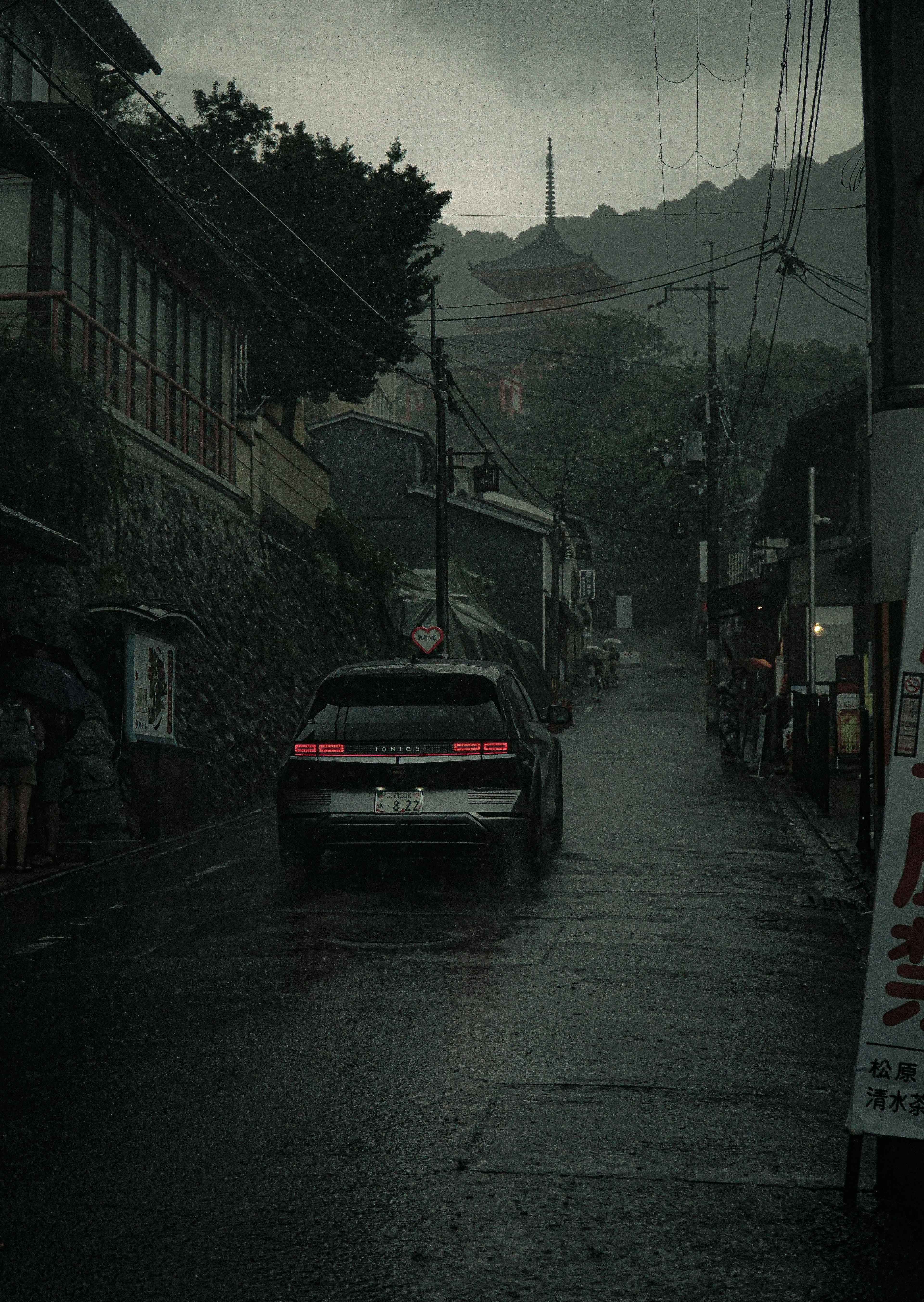 雨の中を走る車と古い建物のある暗い通り