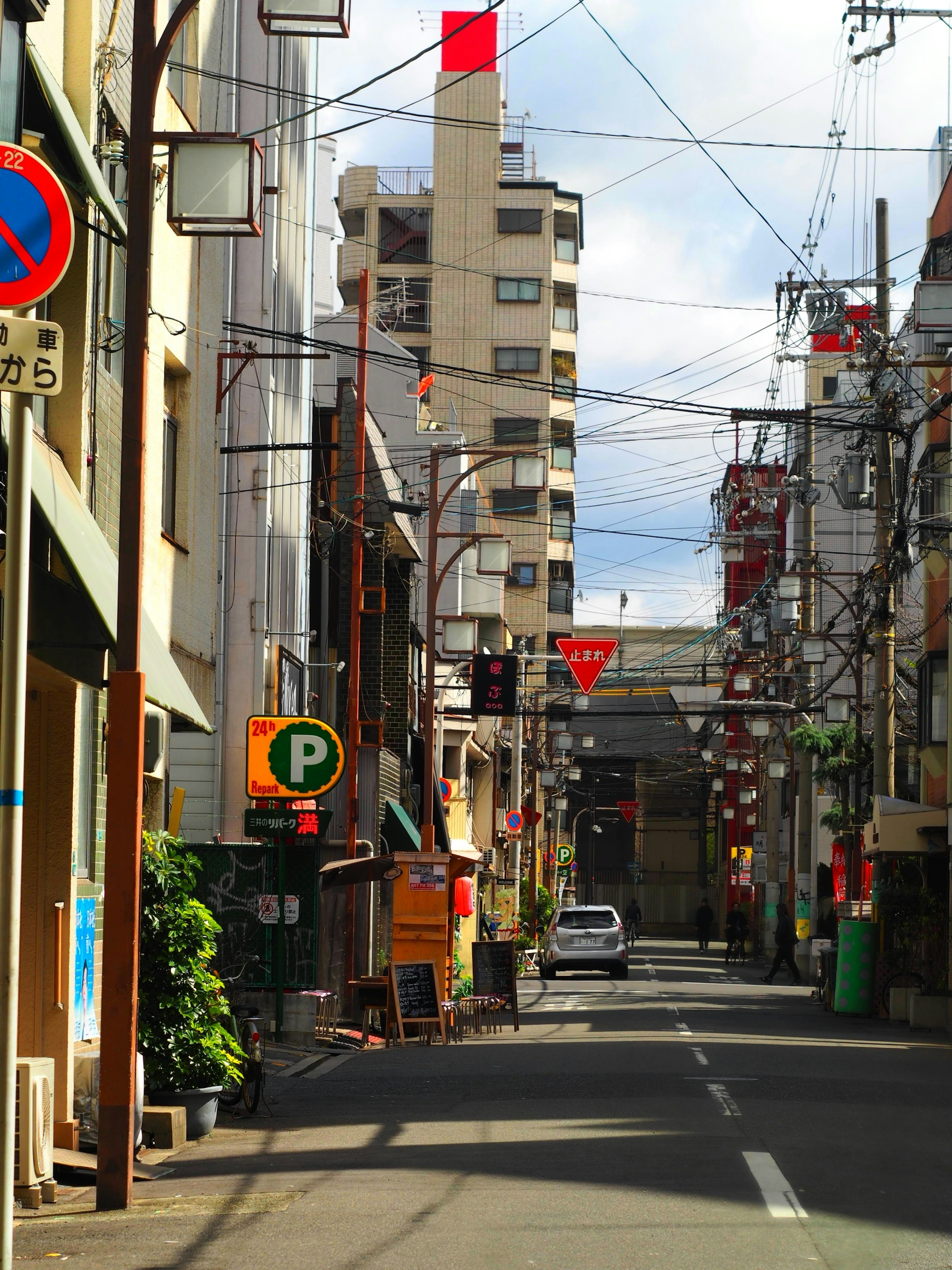 Quiet urban street featuring tall buildings and overhead wires