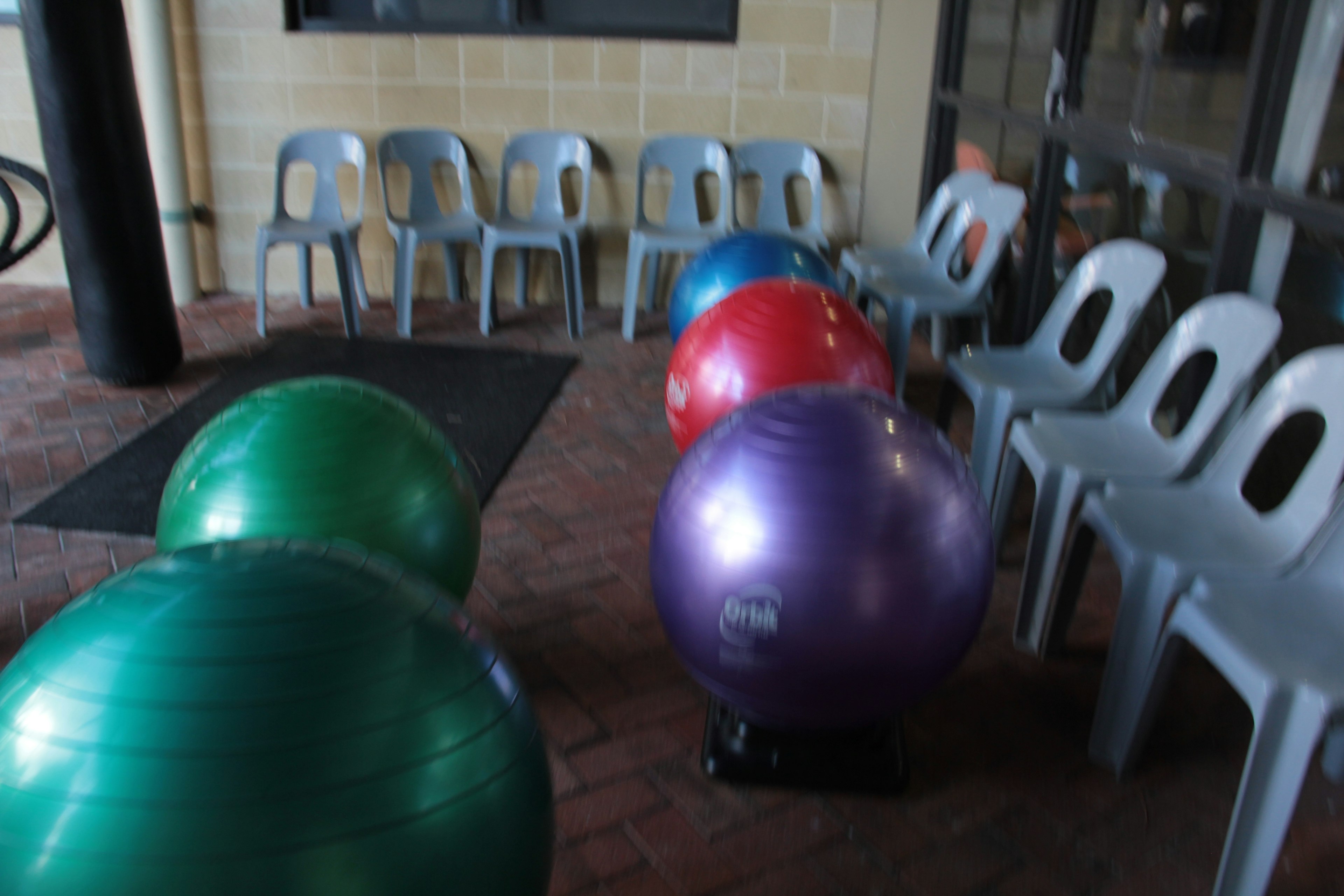 Colorful exercise balls and plastic chairs arranged in an indoor setting