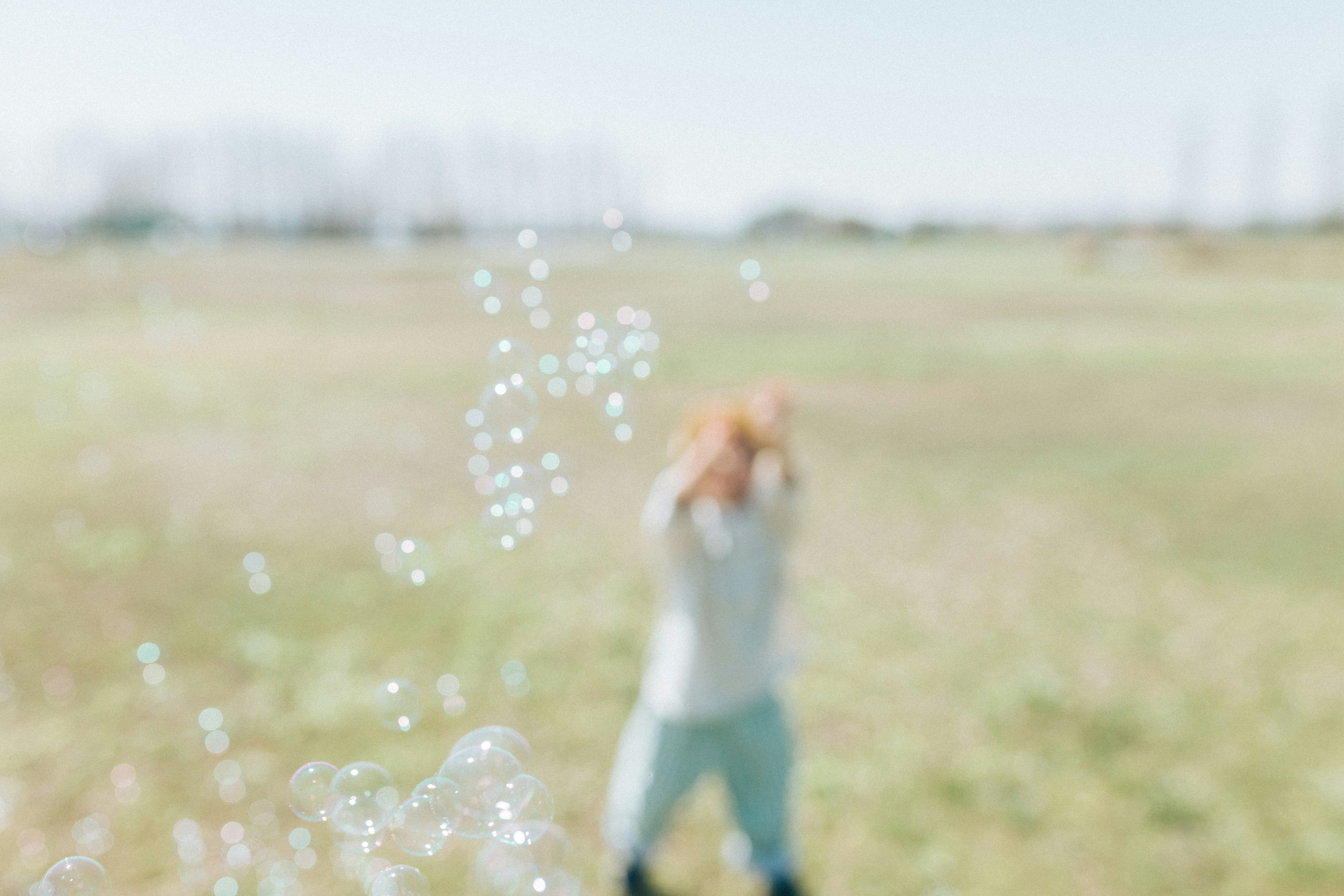 Enfant jouant avec des bulles dans un champ ouvert