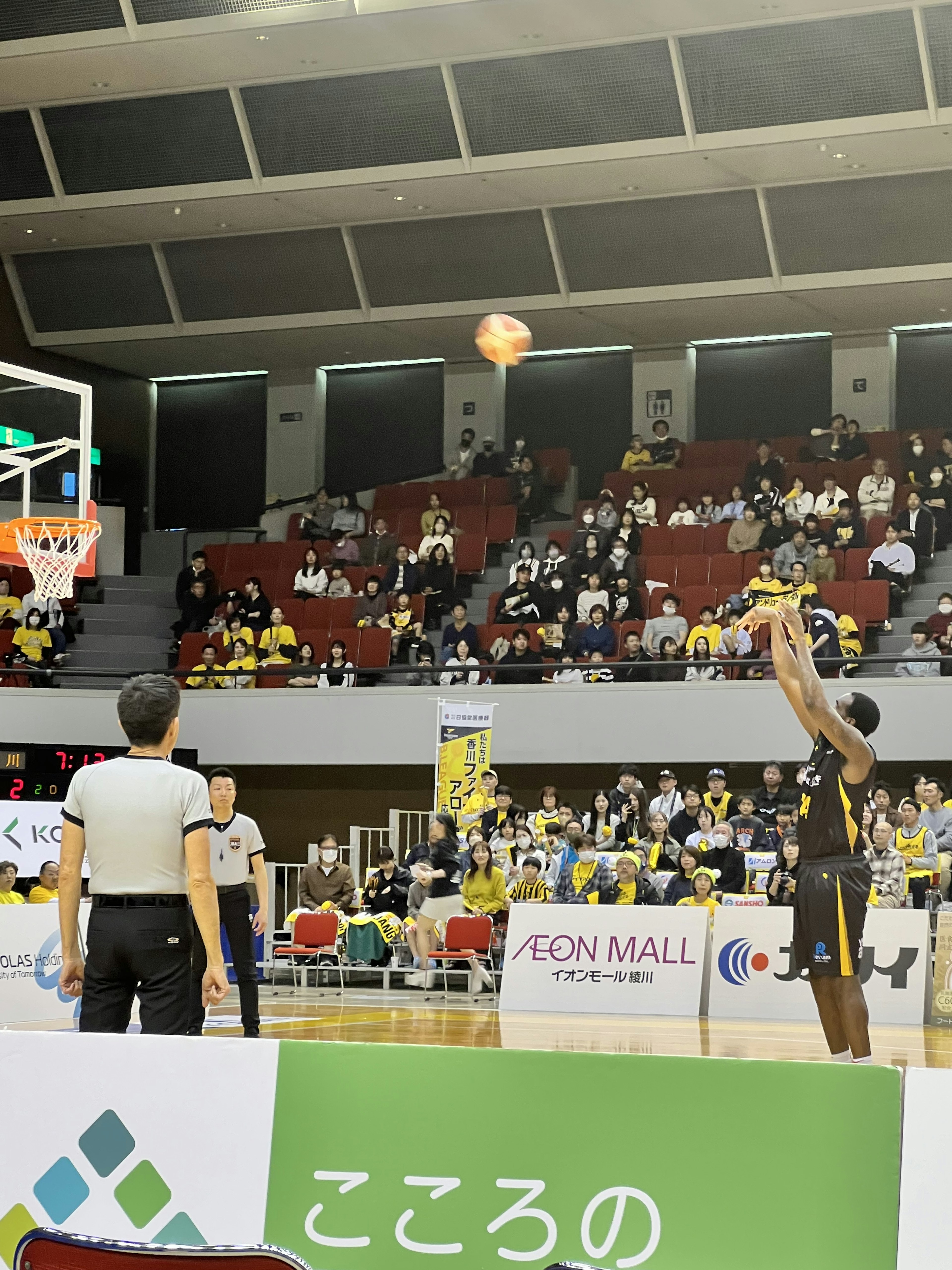 Un jugador de baloncesto lanzando con espectadores al fondo