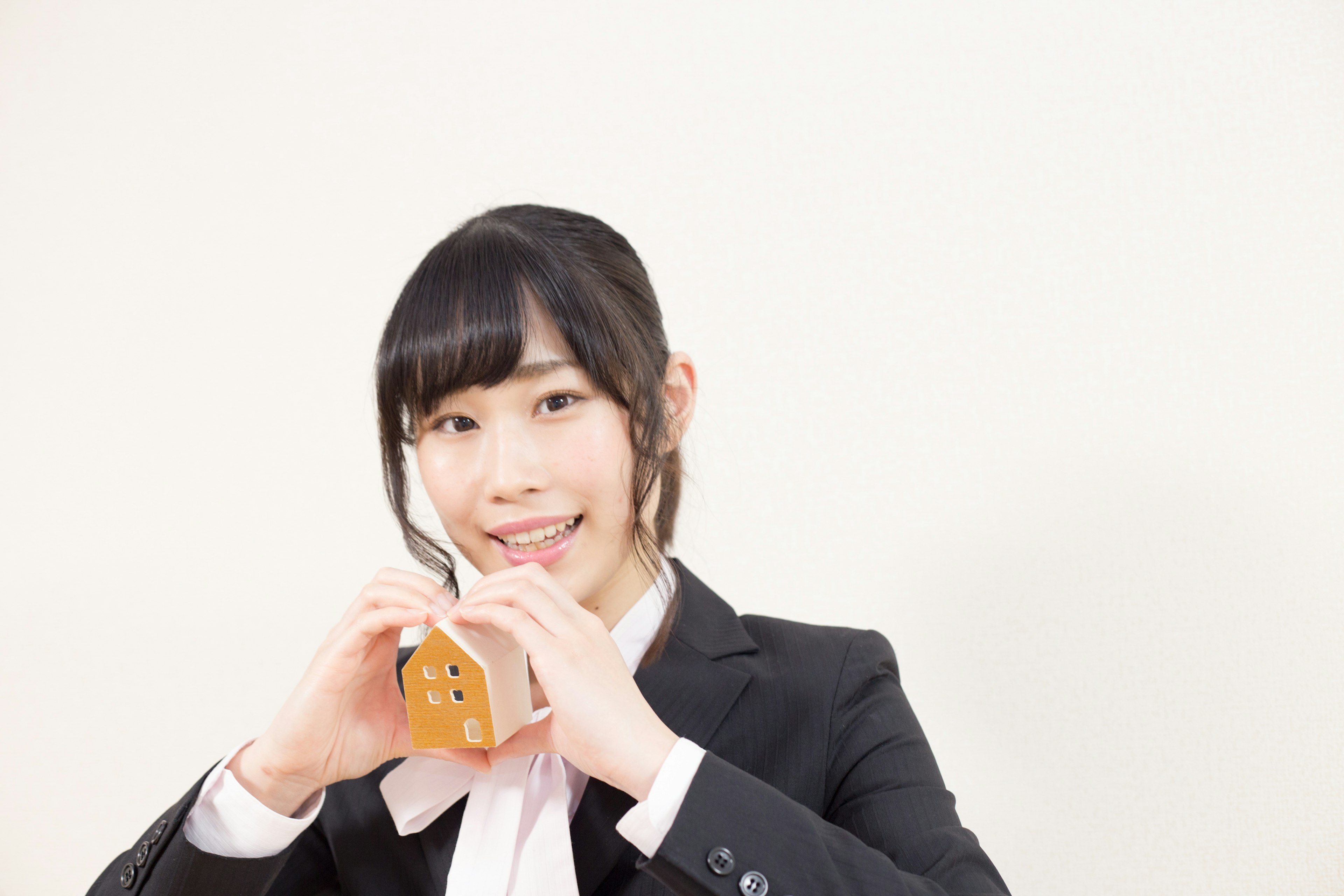 A woman in a suit making a heart shape while holding a snack box