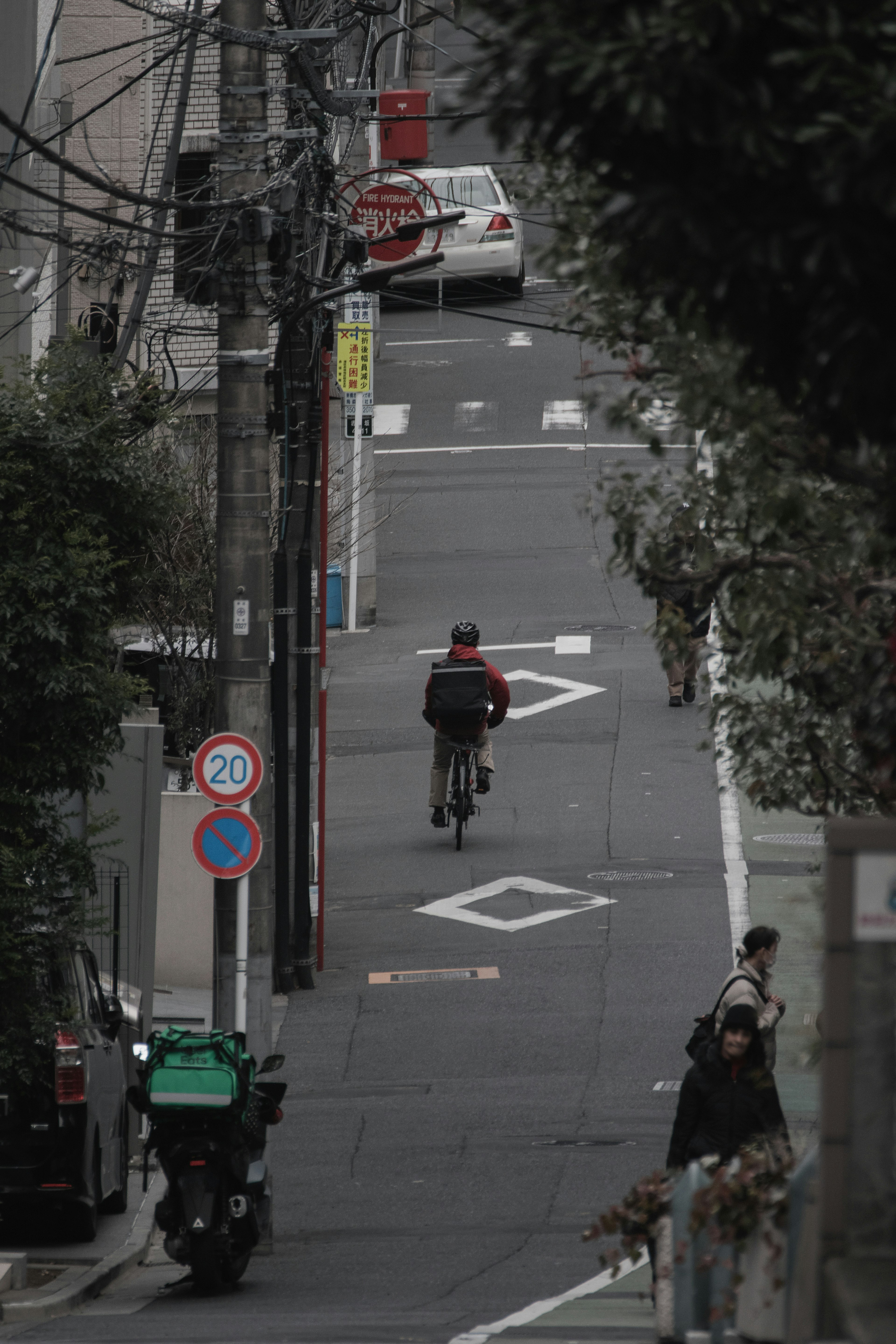 一個人在狹窄的街道上騎自行車，旁邊有交通標誌