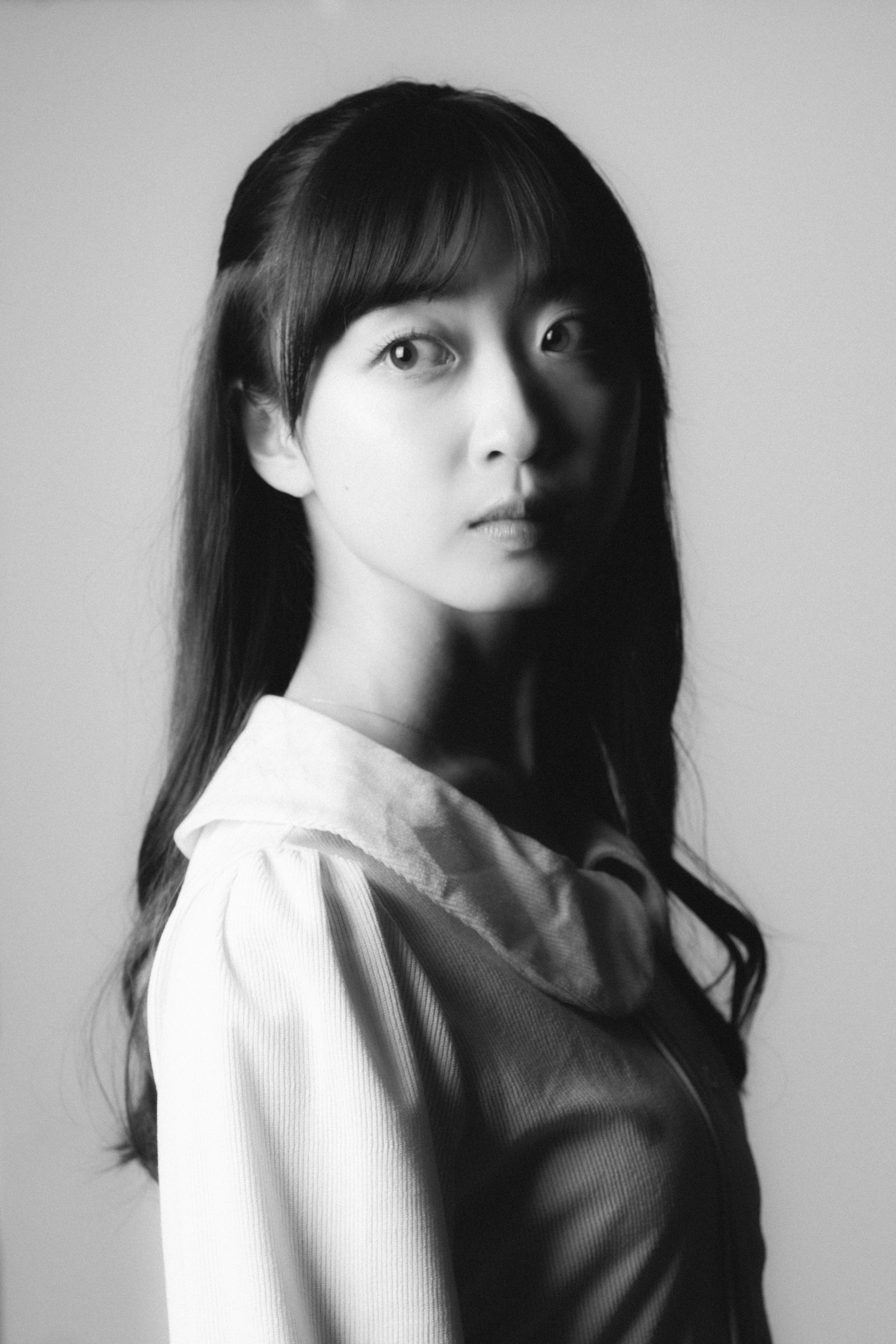 Retrato en blanco y negro de una mujer con cabello largo y lacio usando una camisa mostrando una expresión seria