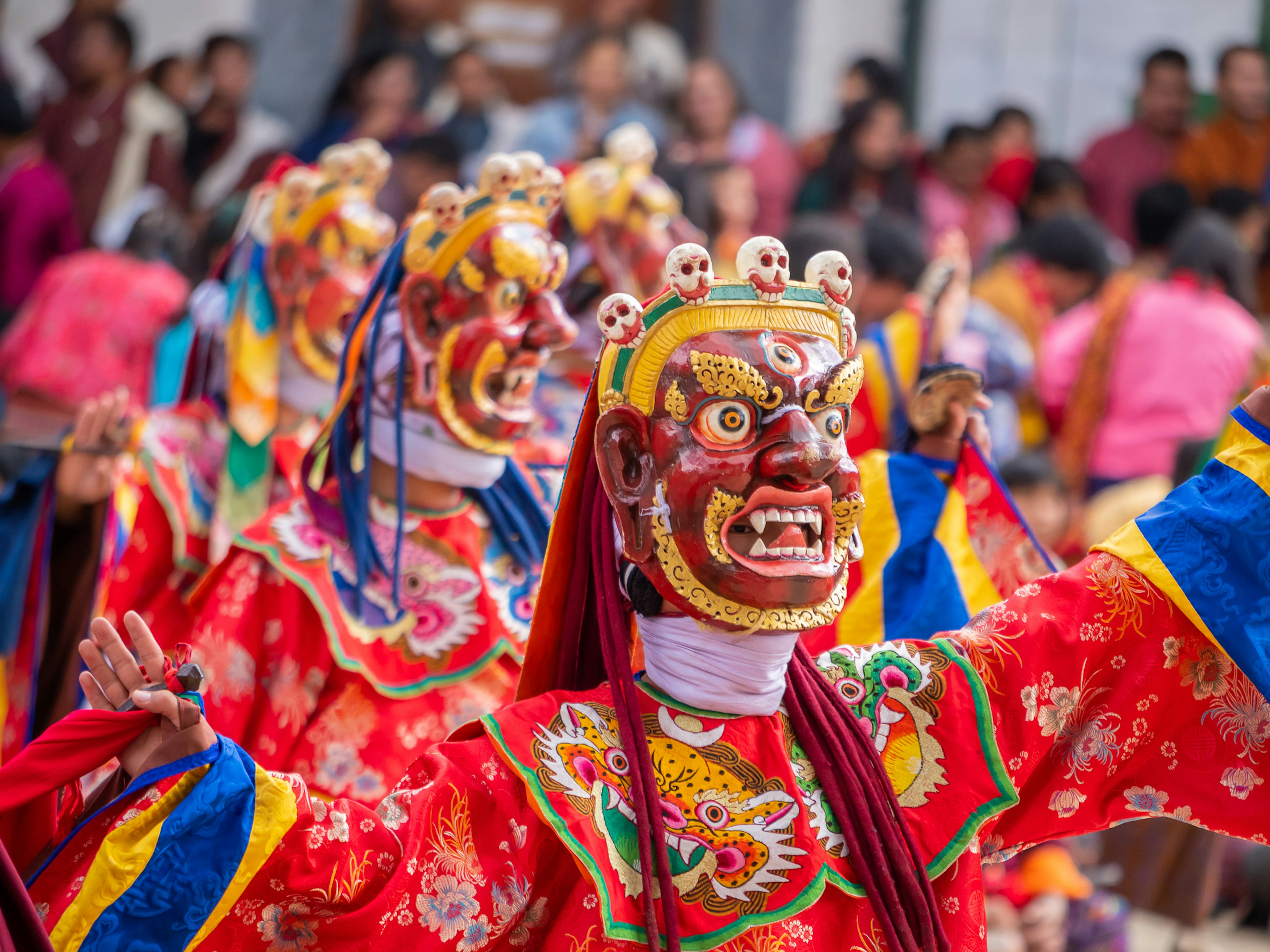 Traditional masked performers in vibrant costumes dancing at a cultural festival