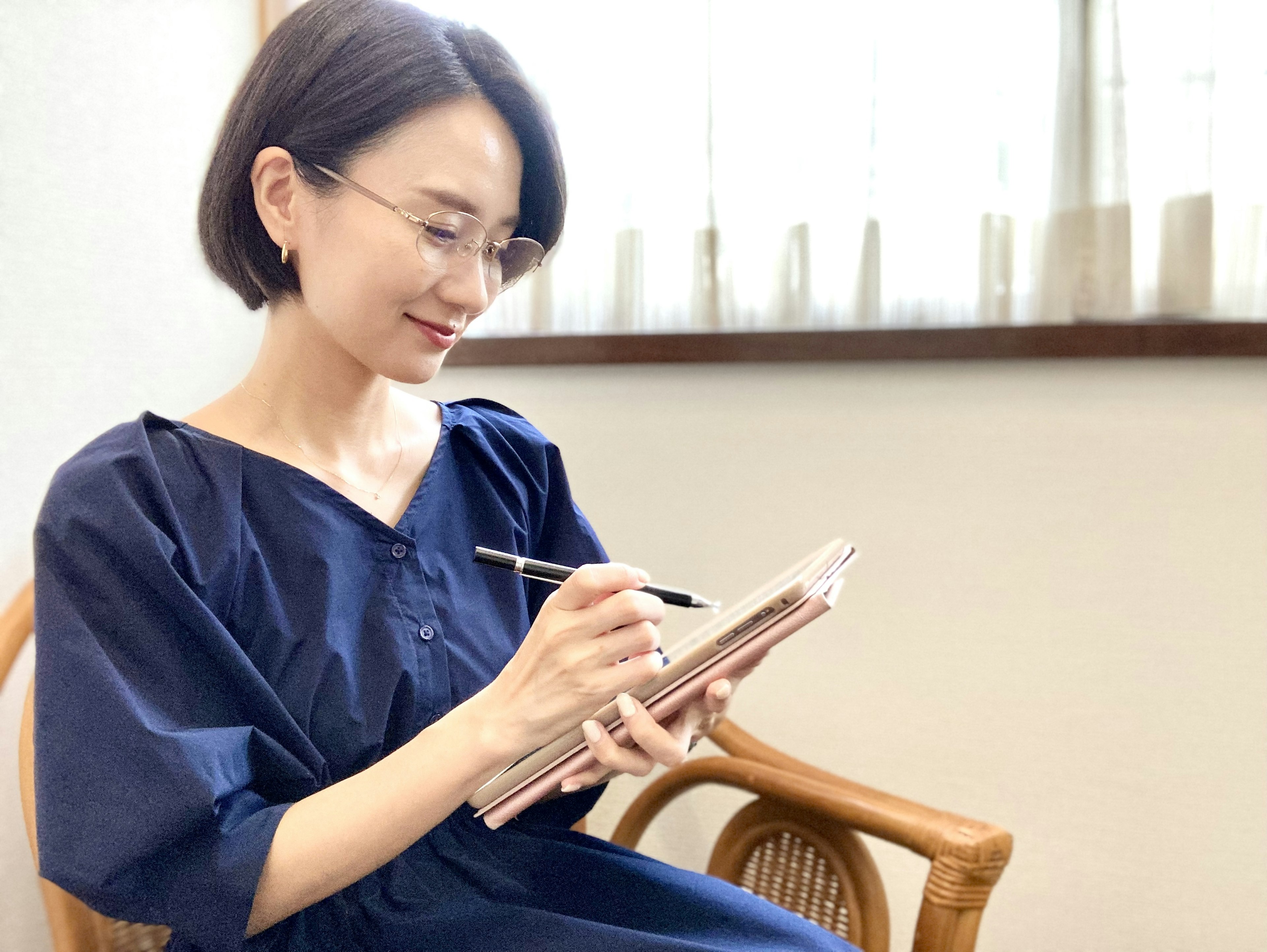 Frau in einem blauen Kleid, die drinnen in ein Notizbuch schreibt