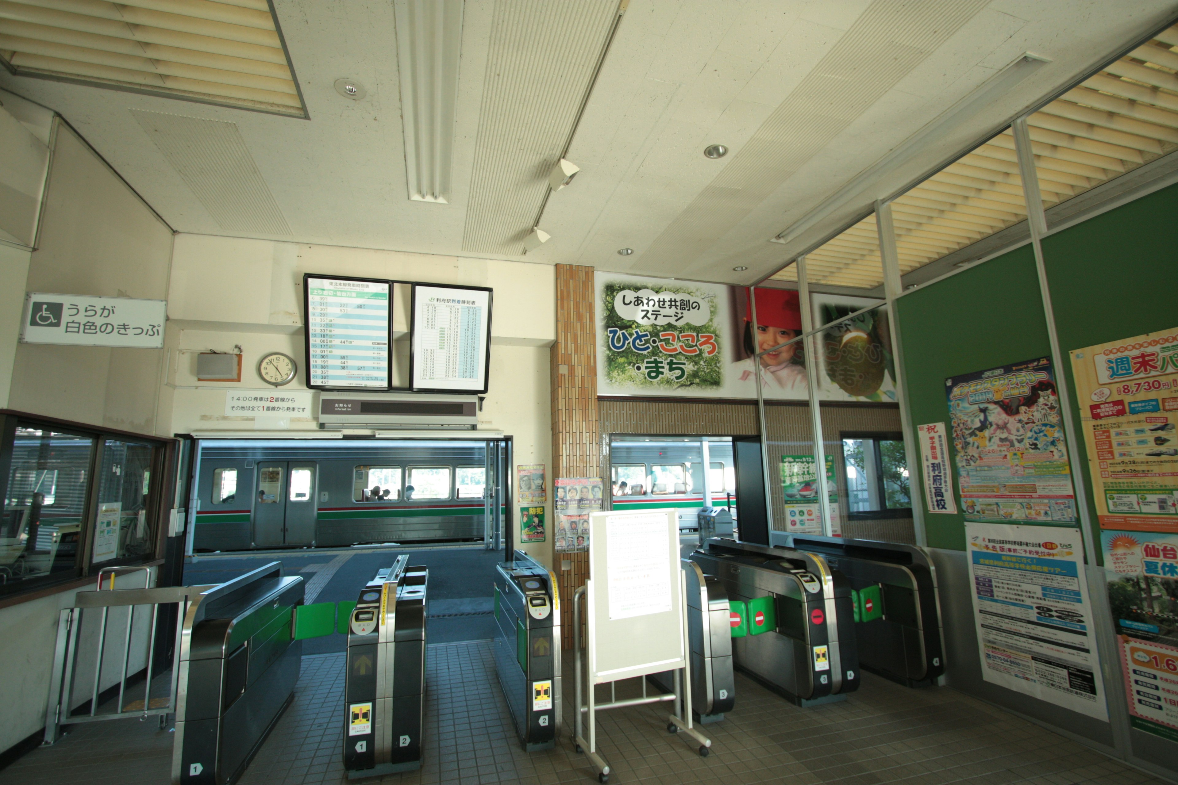 Interior view of a train station ticket gate with advertisements