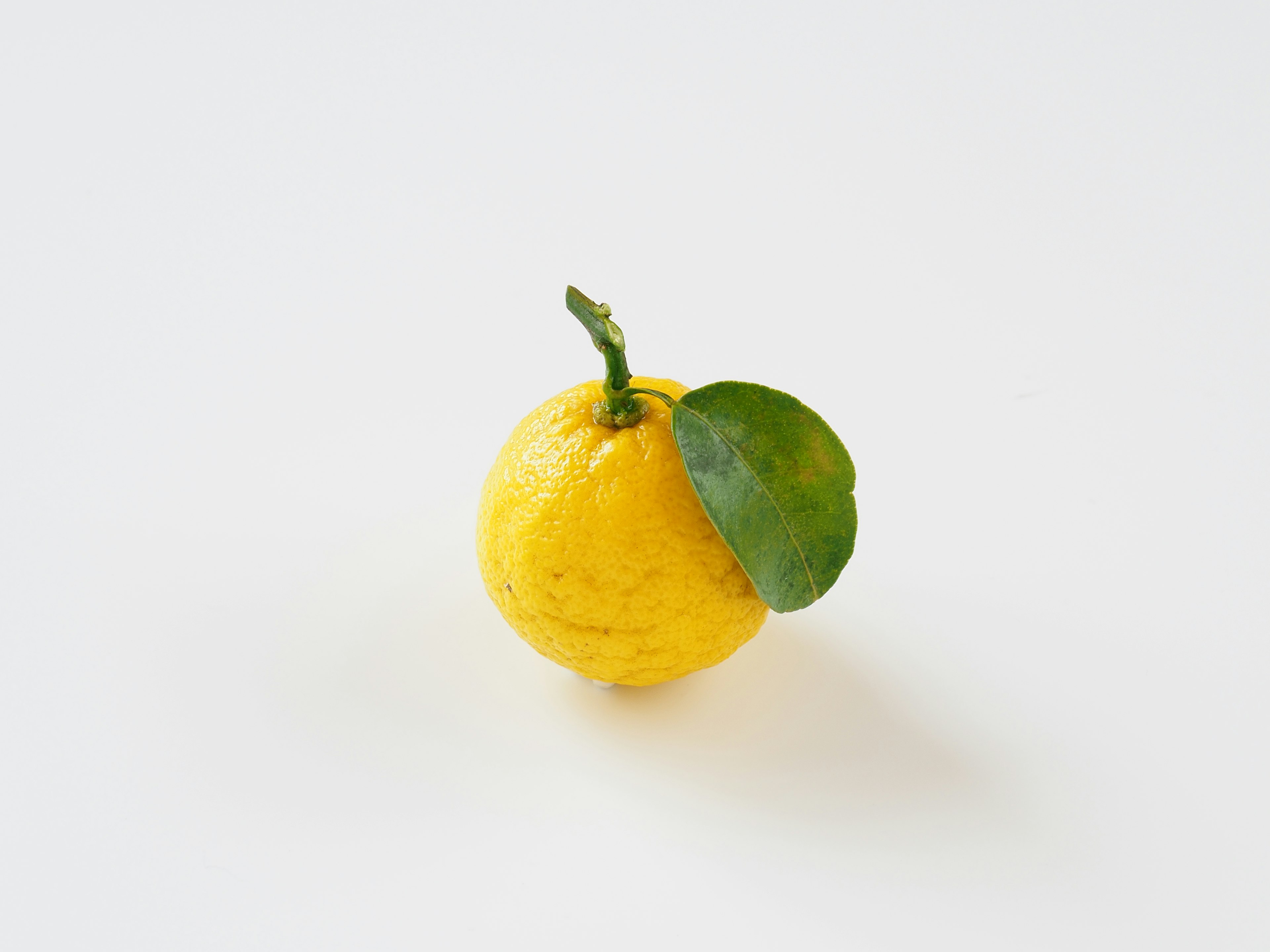 Yellow lemon with a green leaf attached