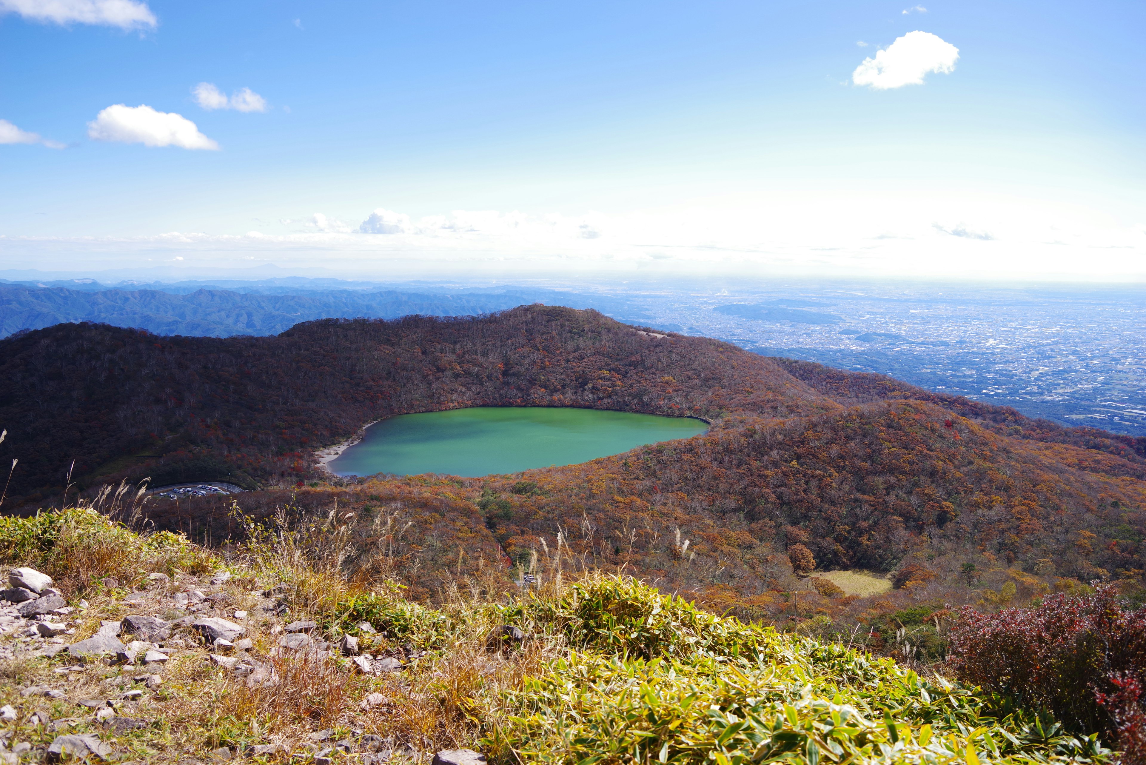 Vista escénica desde la cima de una montaña con un lago verde y follaje otoñal