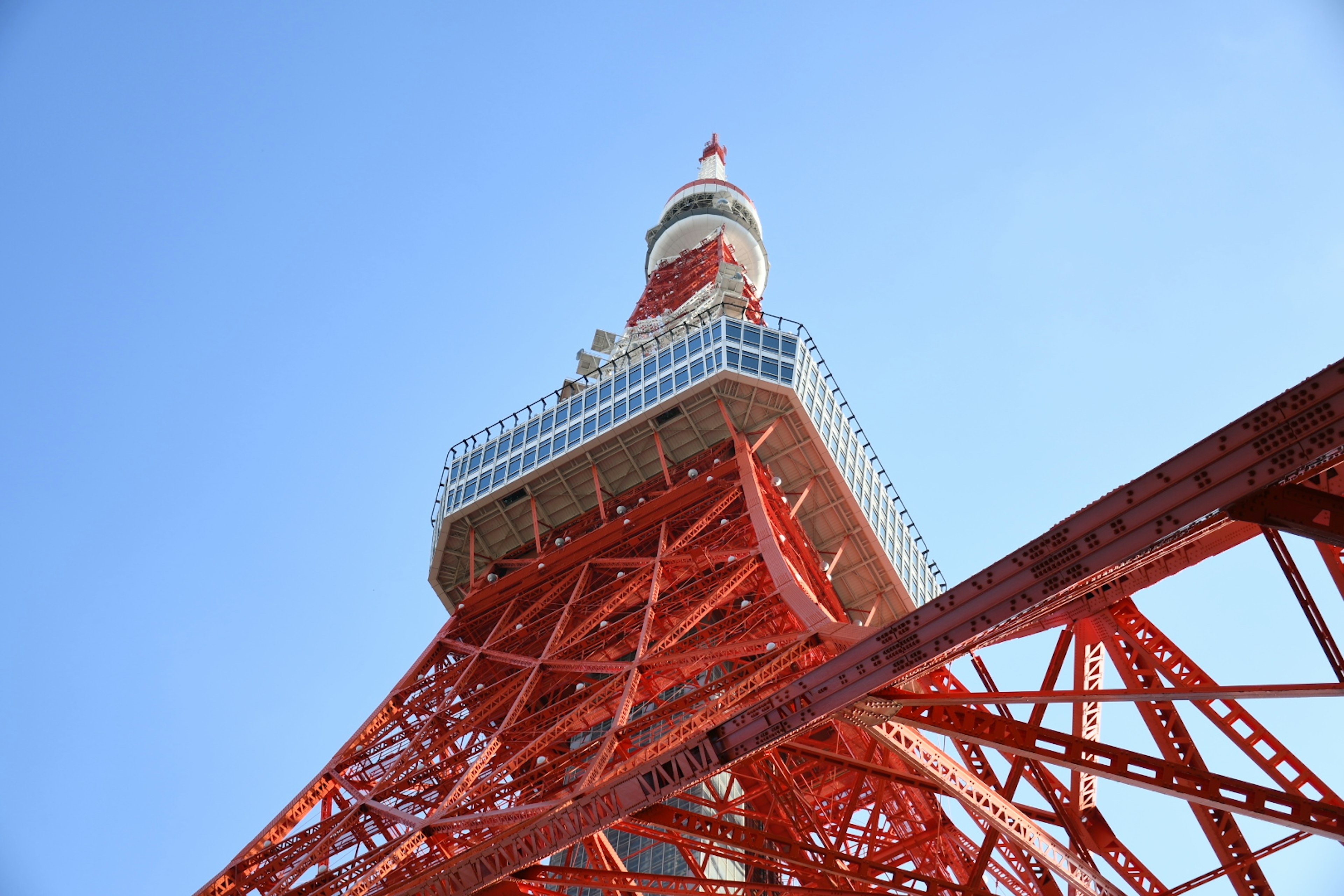 Menara Tokyo dengan struktur merahnya di latar belakang langit biru cerah dari sudut rendah