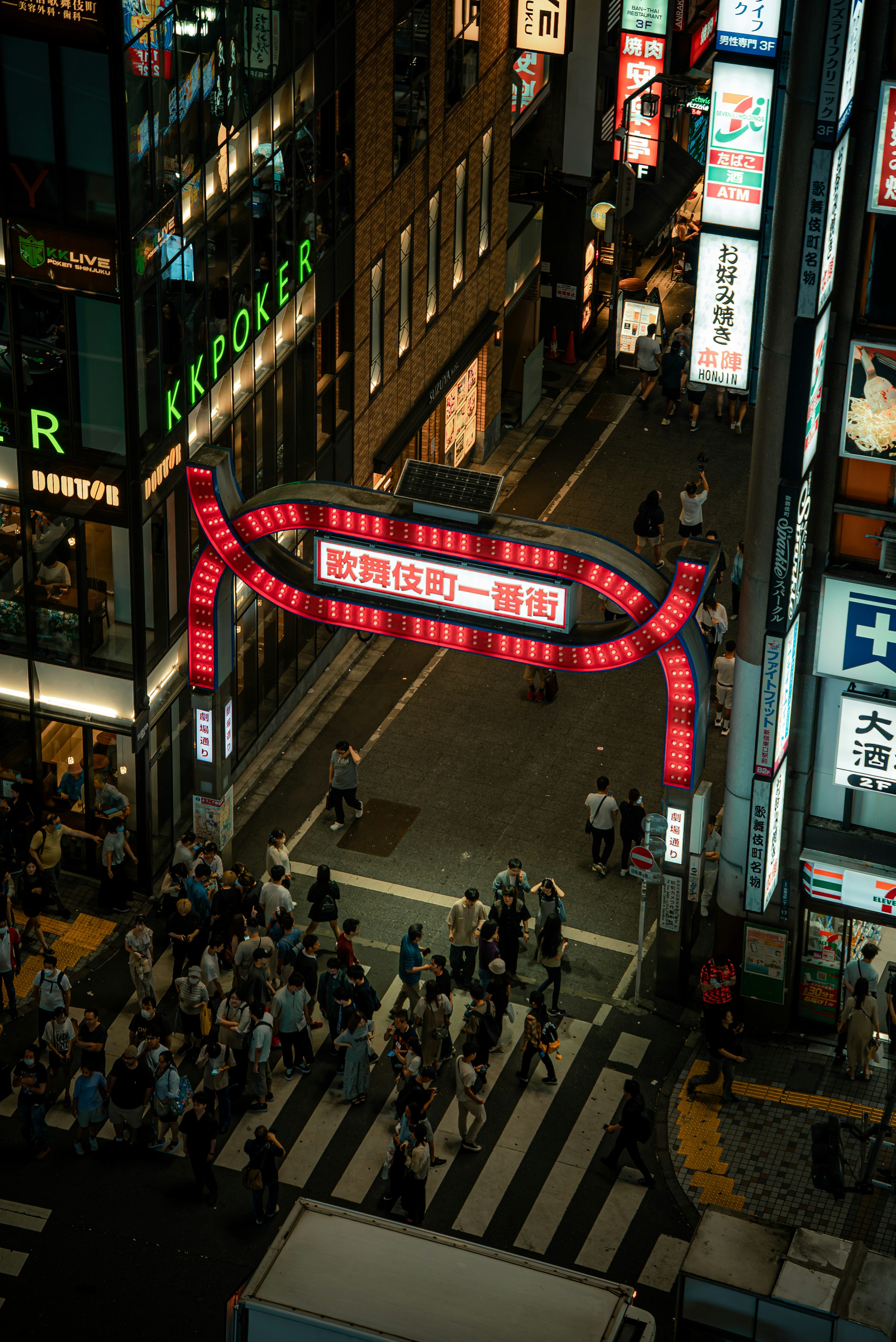 夜の街並みを彩る赤いアーチの看板と人々の賑わい