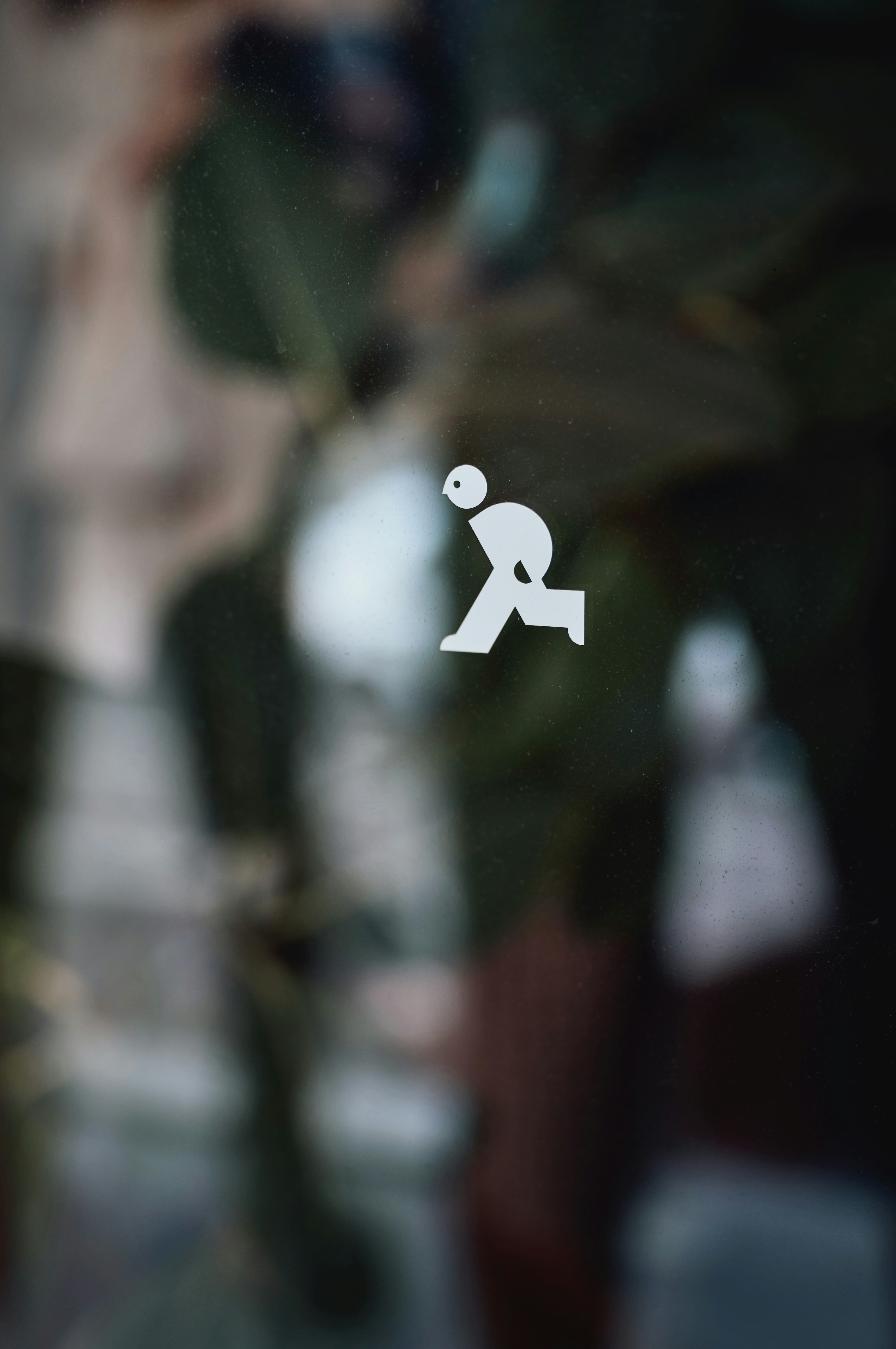 White pictogram of a person walking in front of green leaves