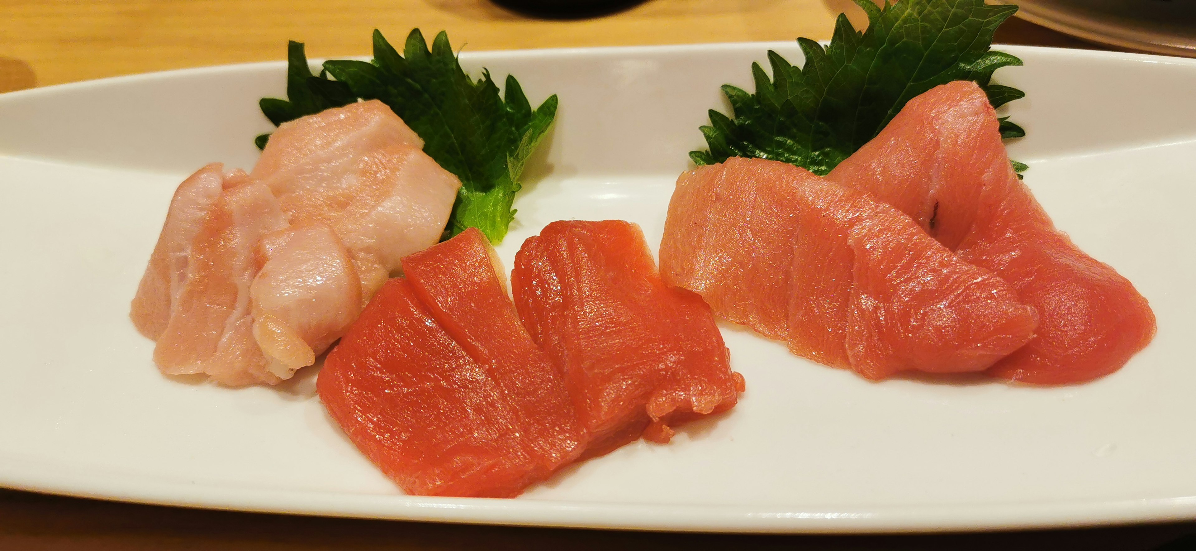 Piring sashimi segar dengan potongan tuna merah dan lemak tersusun dengan indah