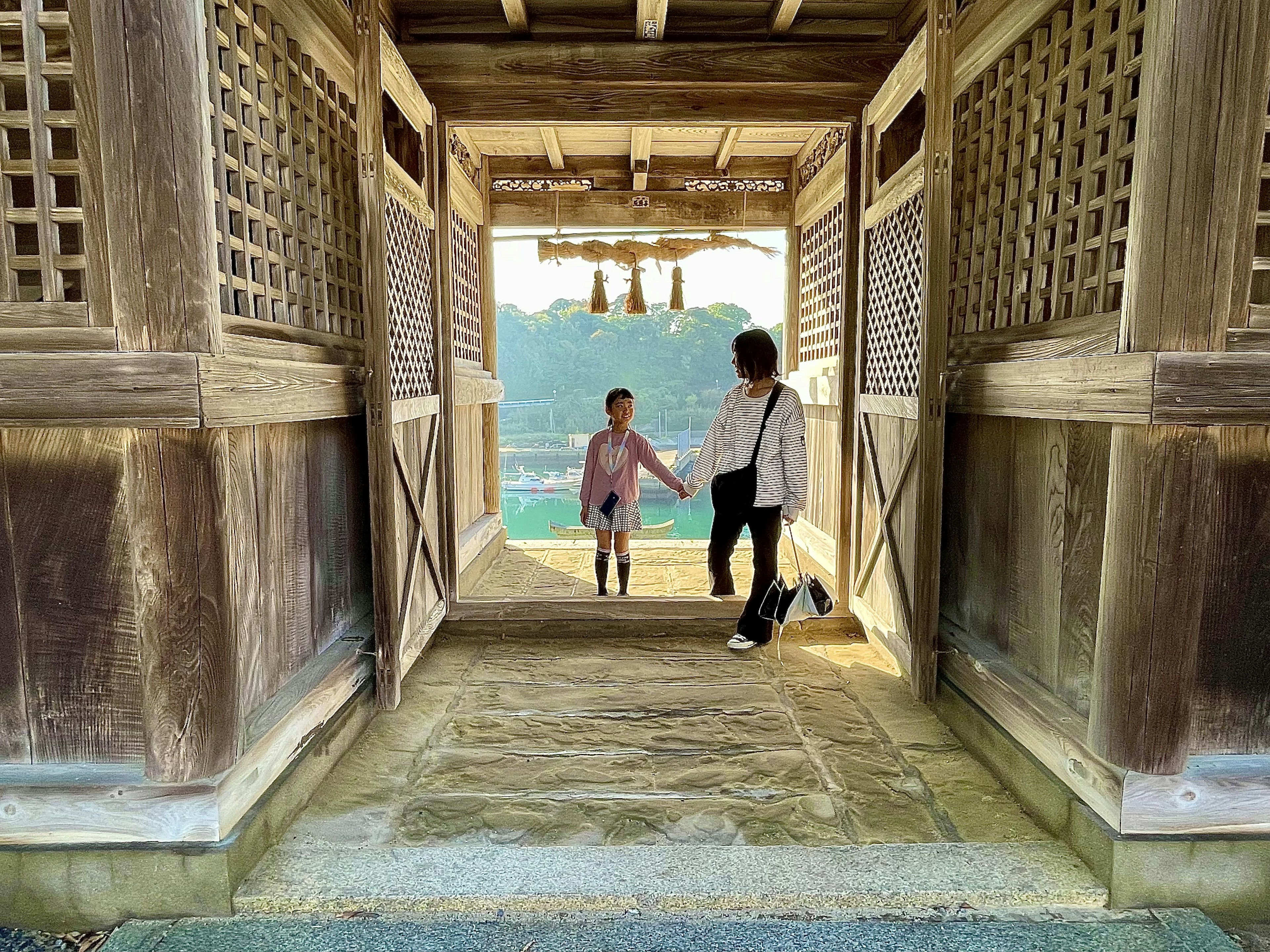 Dua anak bergandeng tangan di dalam struktur kayu tradisional