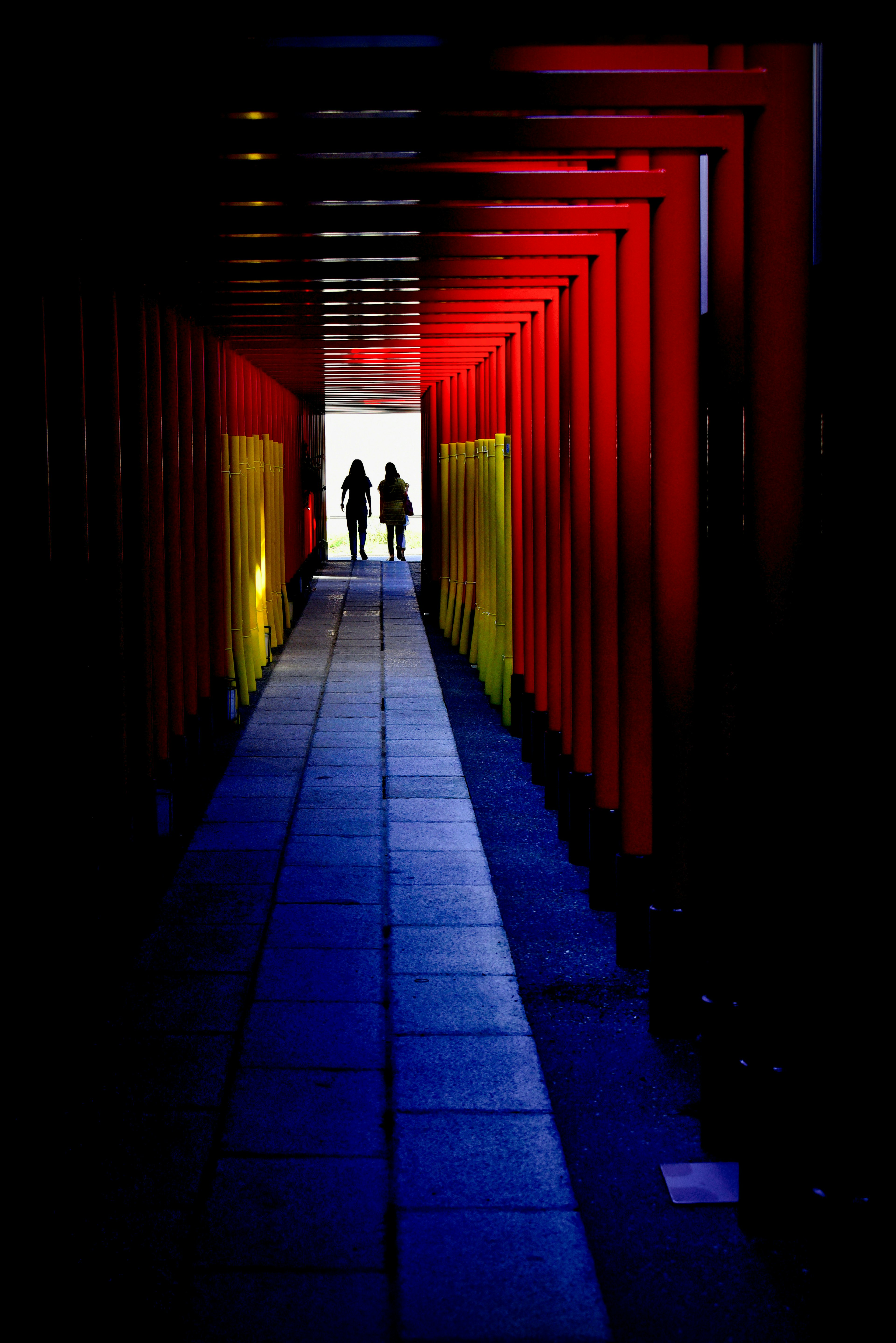 Silhouetten von zwei Personen in einem Tunnel aus roten und gelben Farbtönen