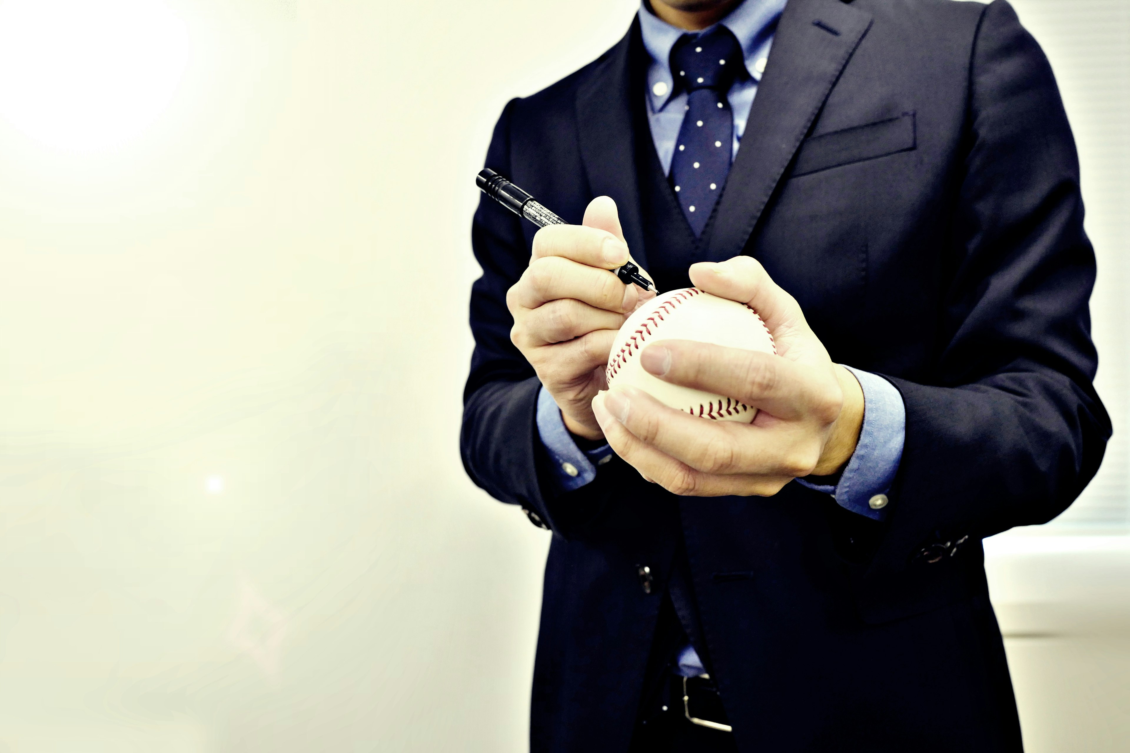 Un hombre en traje firmando una pelota de béisbol