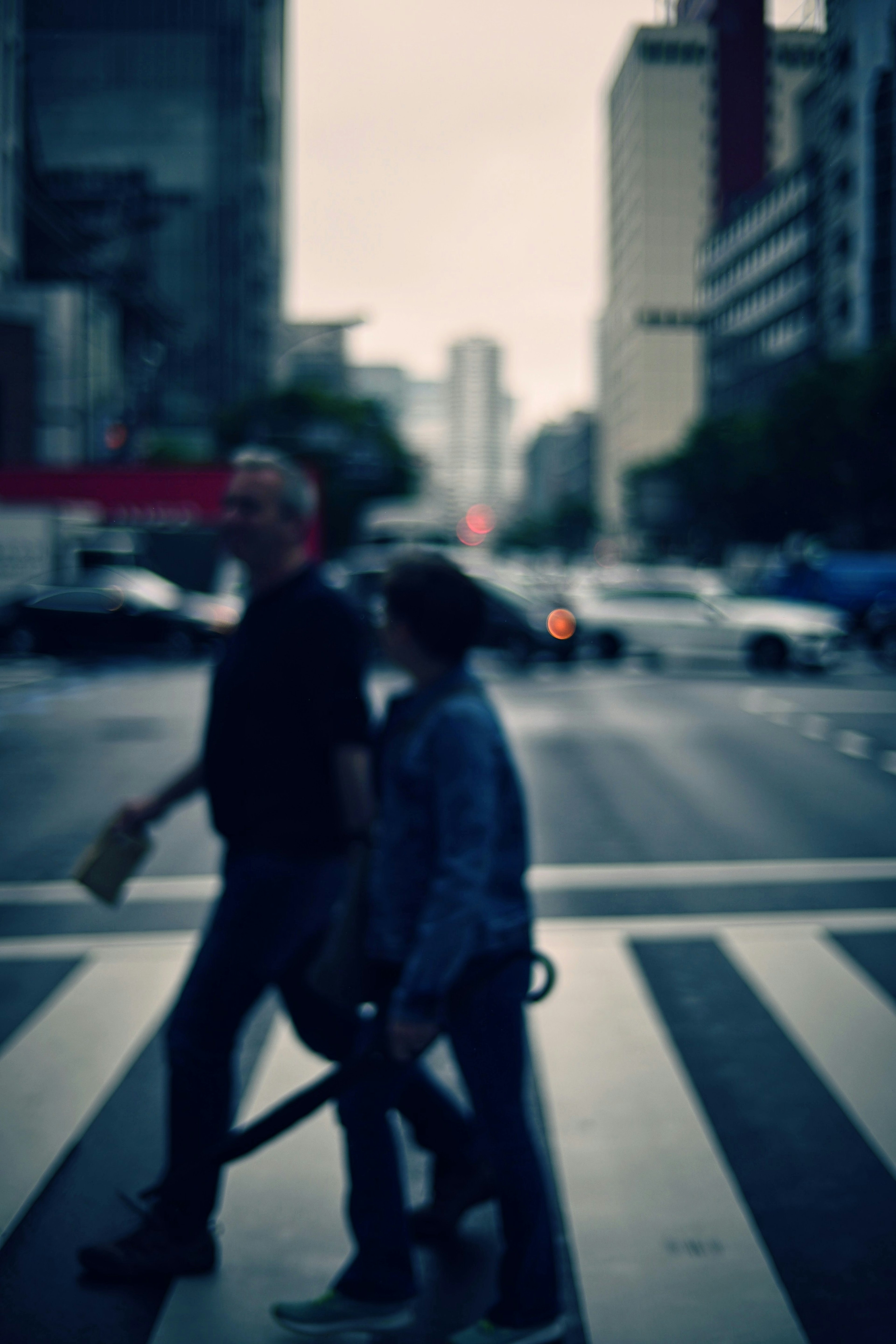 Two people walking in a blurred urban crosswalk