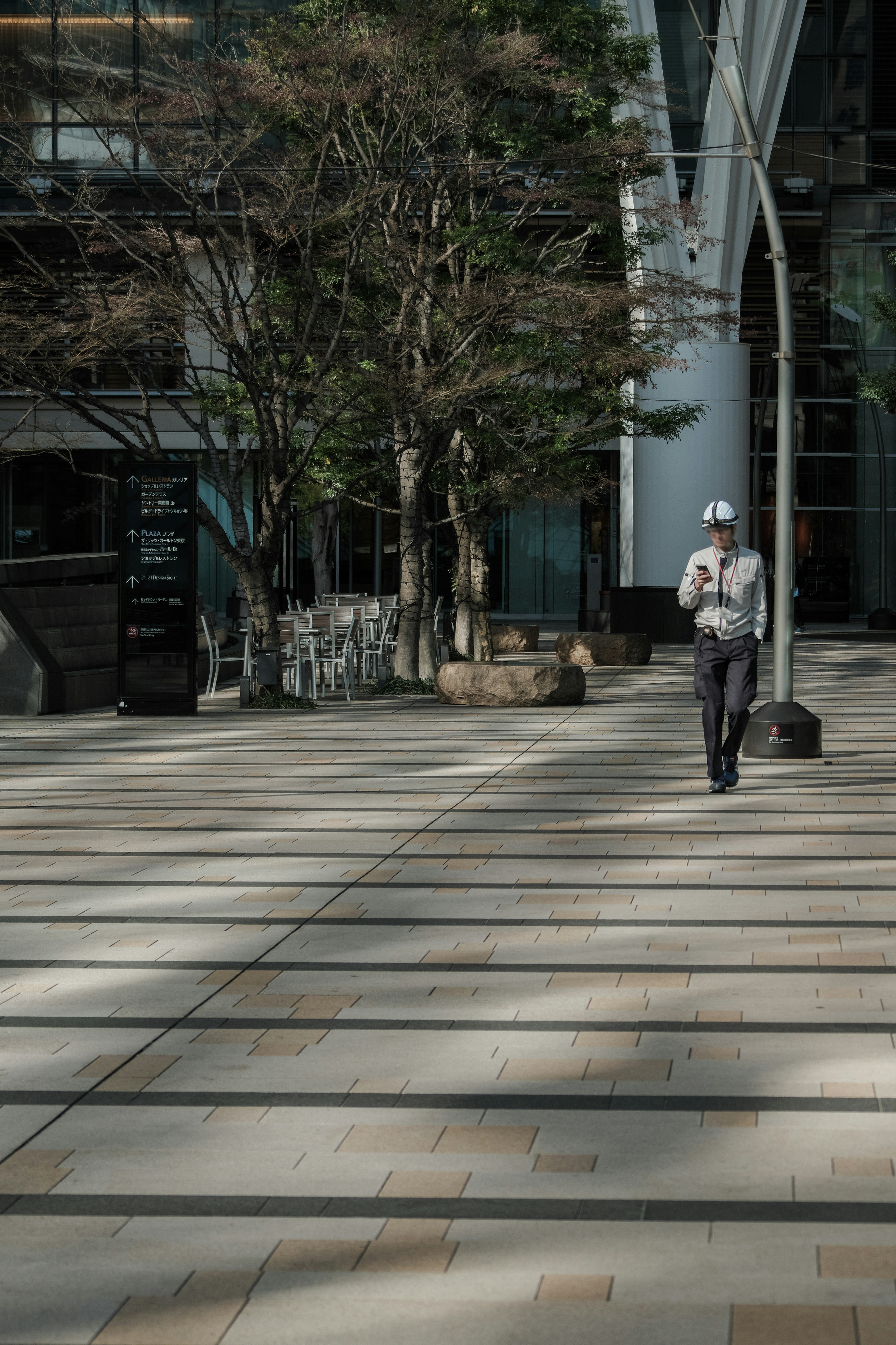 A person walking on a street in front of a building with trees