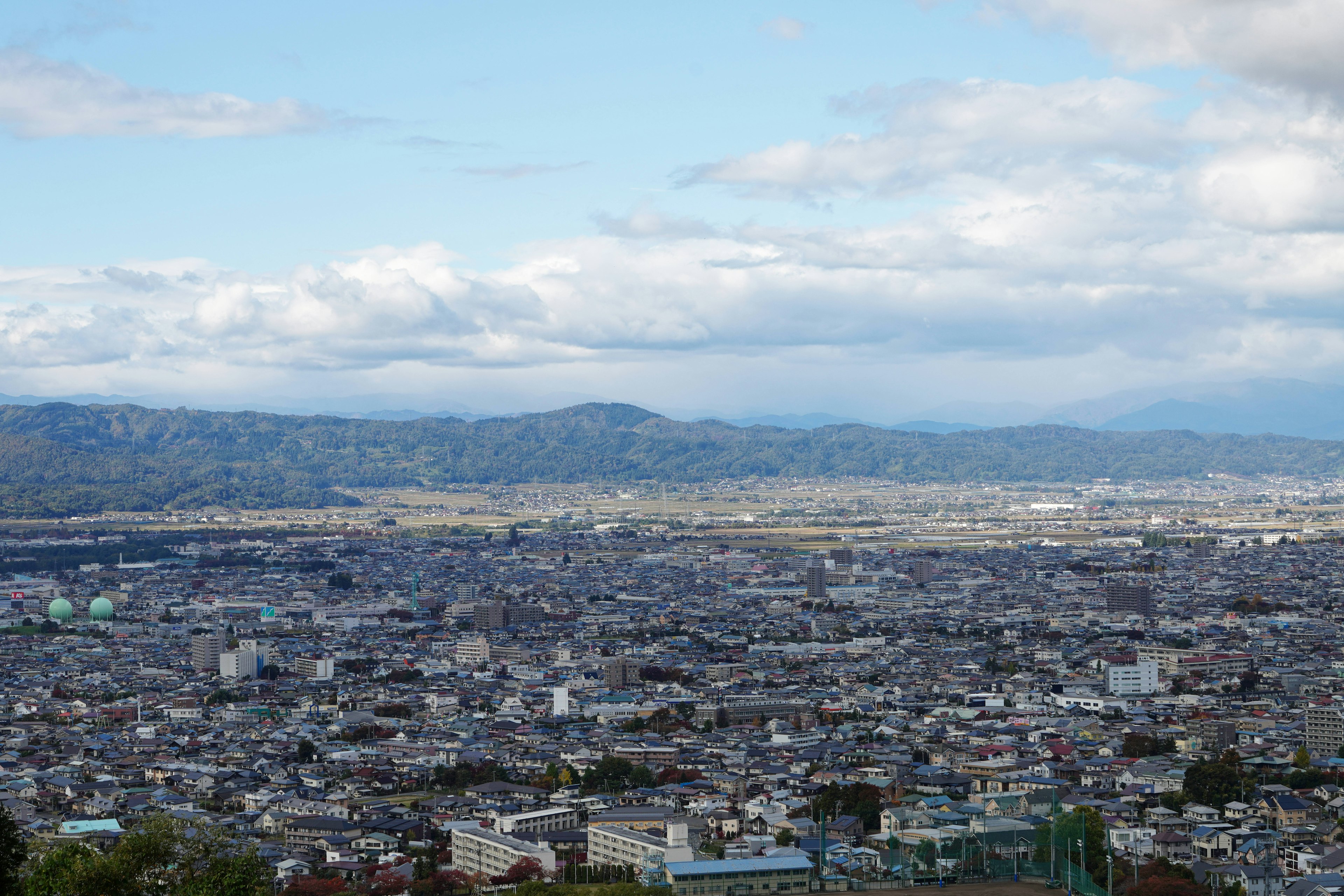 城市的全景，背景有山脉和散布的云朵