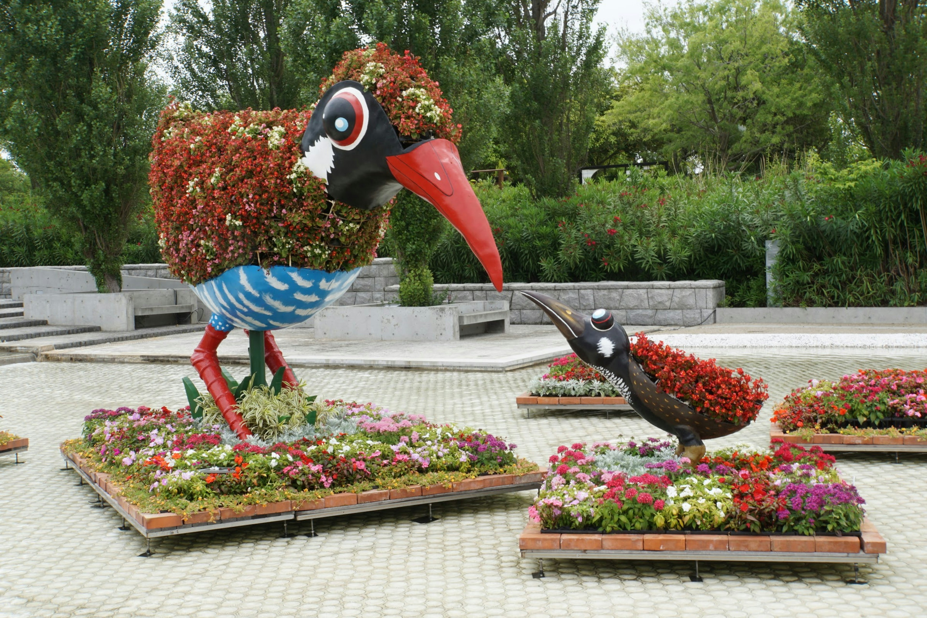 Scena di giardino con sculture di uccelli grandi e piccoli decorate con fiori