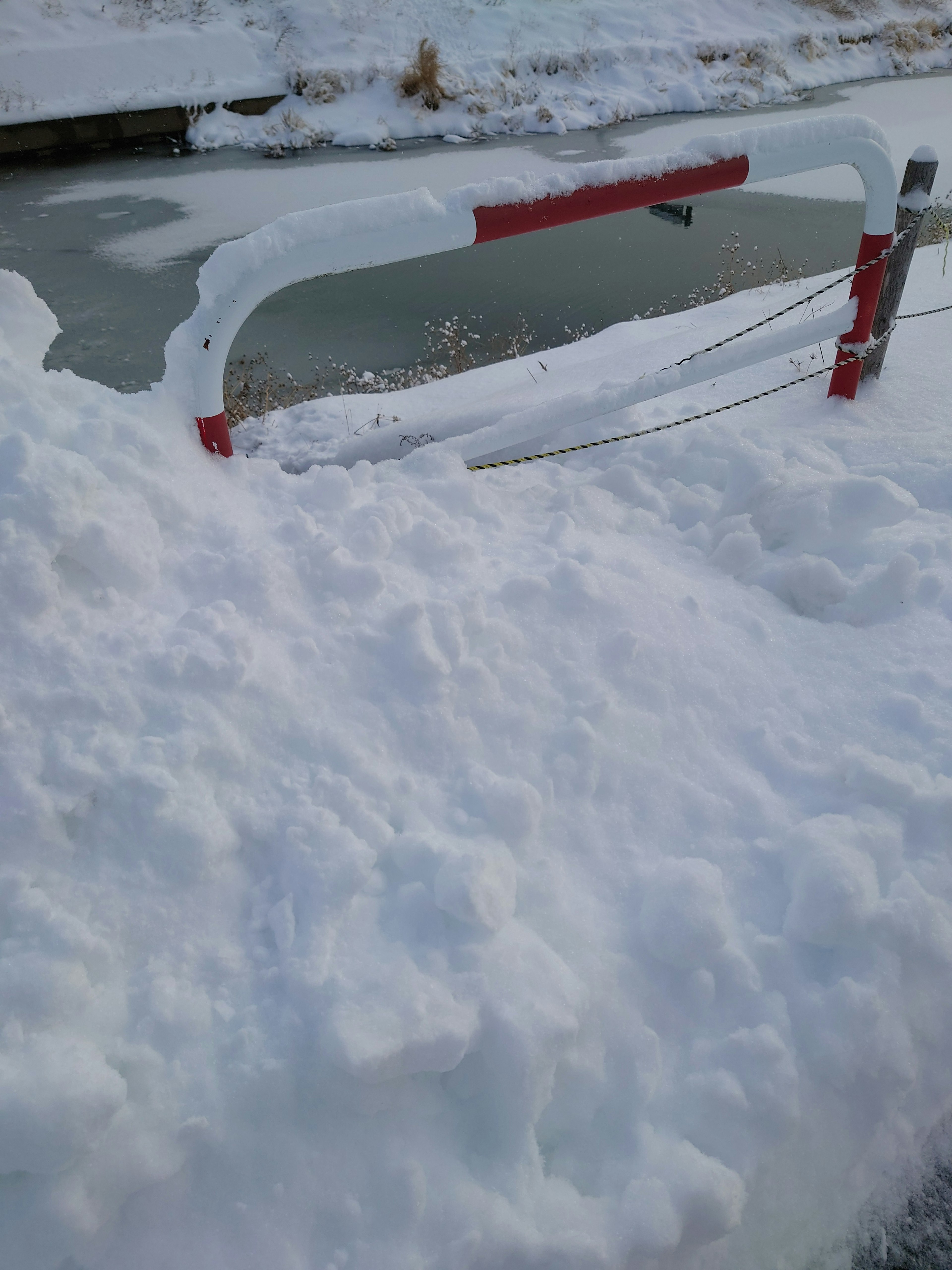 Barriera coperta di neve con acqua ghiacciata sullo sfondo