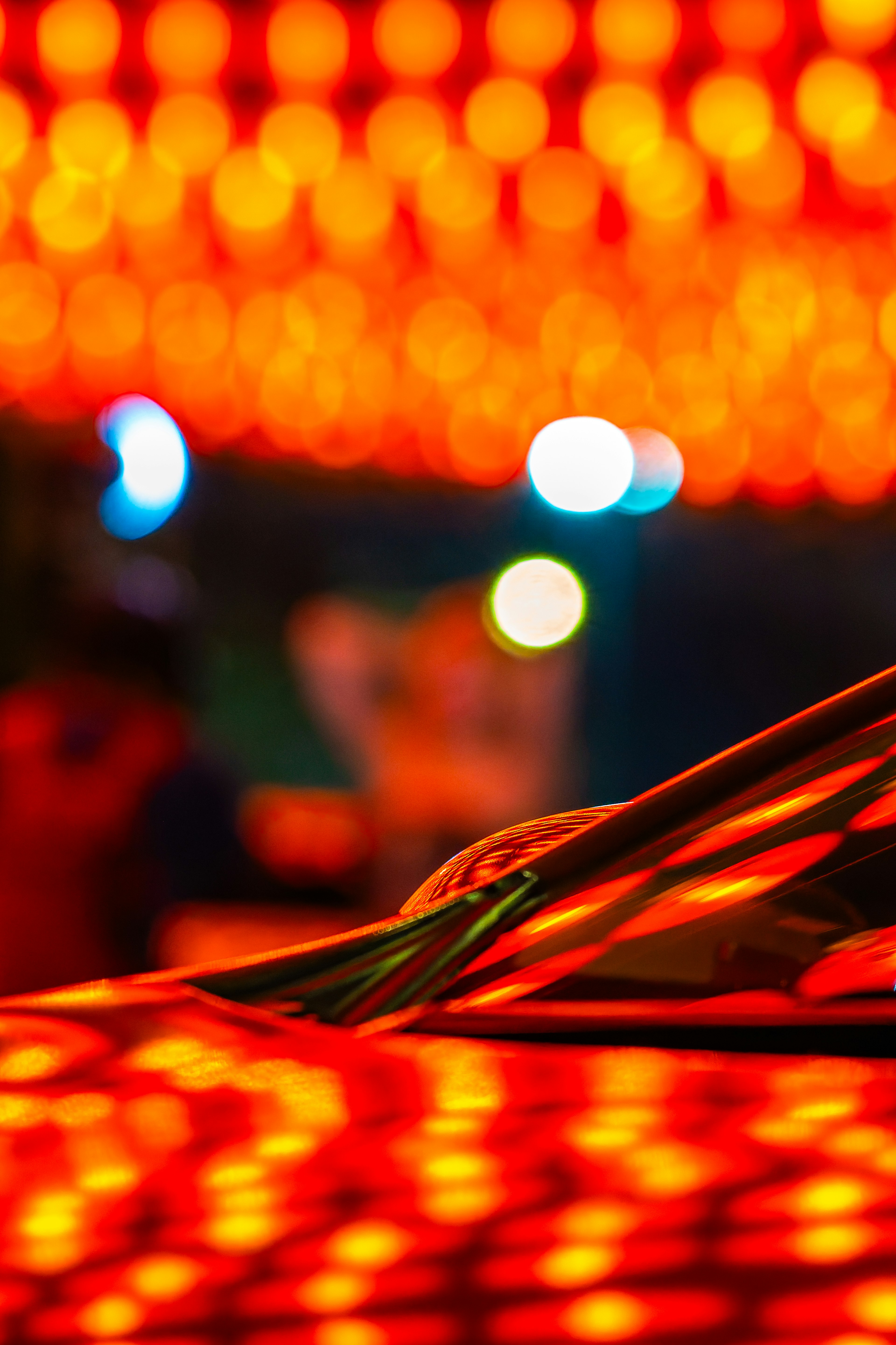 Car body reflecting vibrant red lanterns in the background