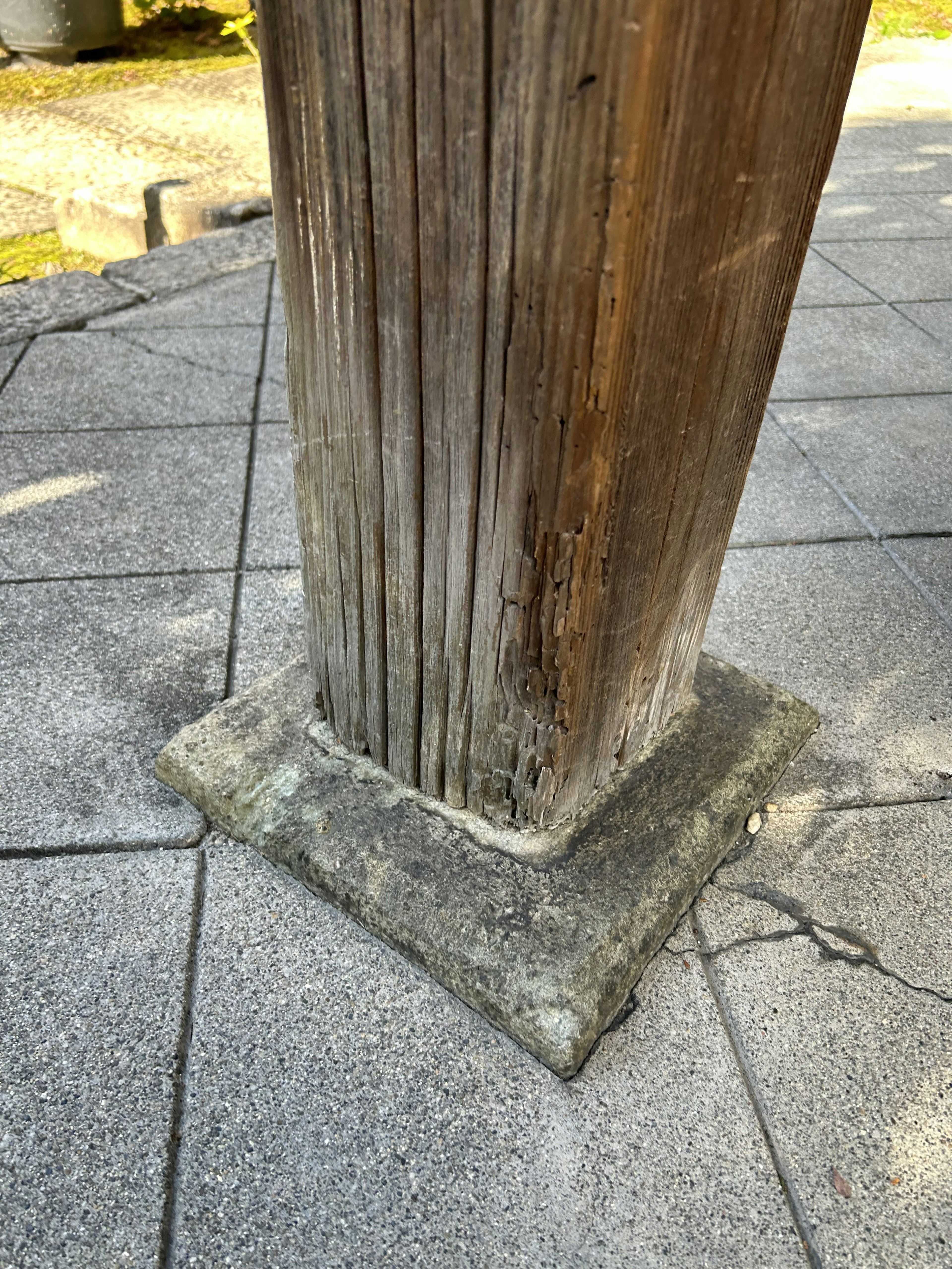 Primo piano di un vecchio palo di legno con base in pietra