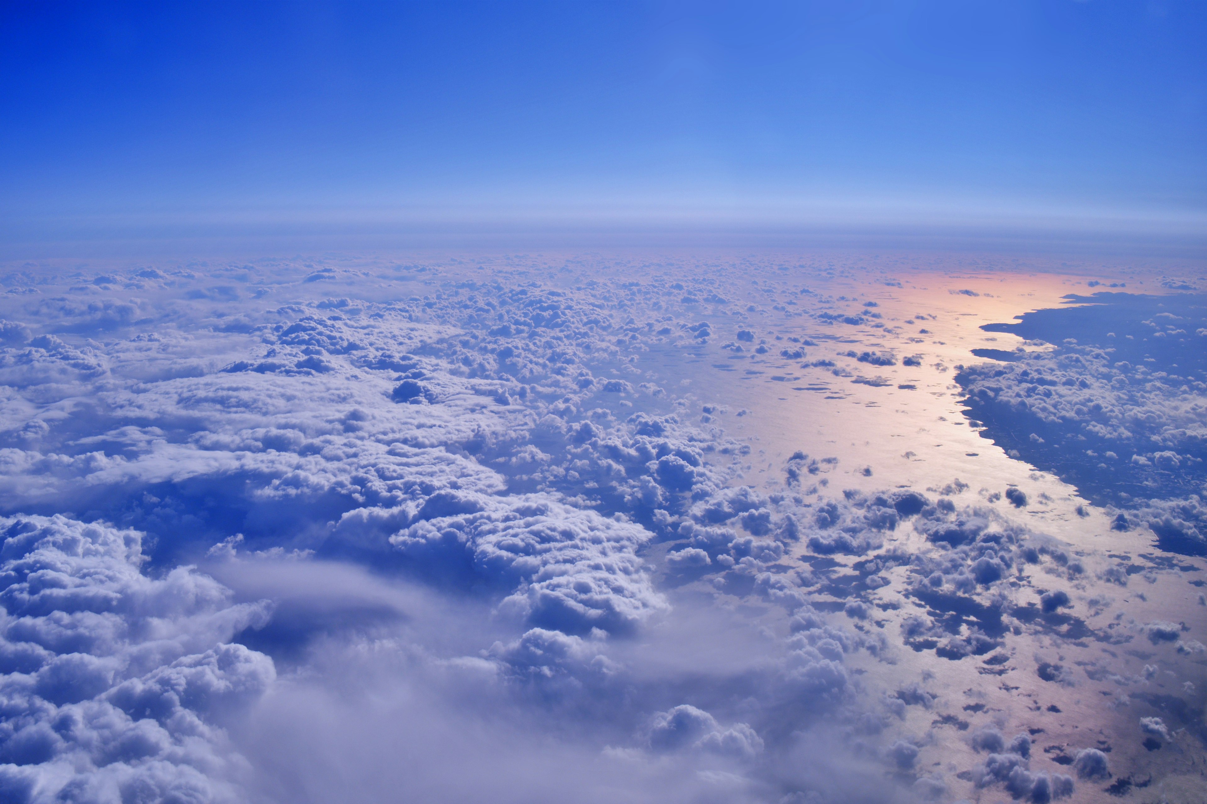 Vasto cielo blu con un mare di nuvole e luce solare che si riflette sulla superficie dell'oceano