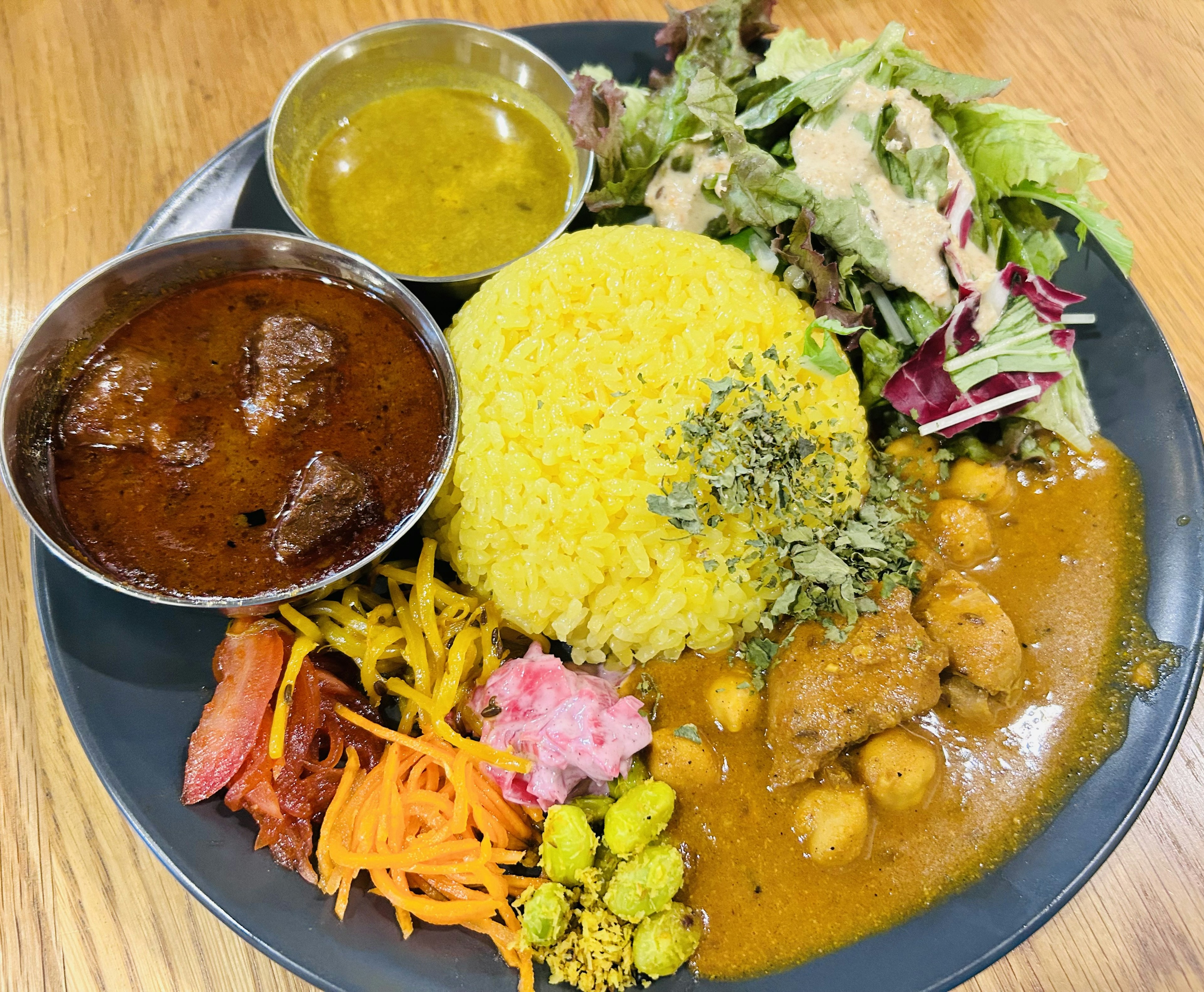 Colorful Indian platter featuring curry, rice, salad, and various sides