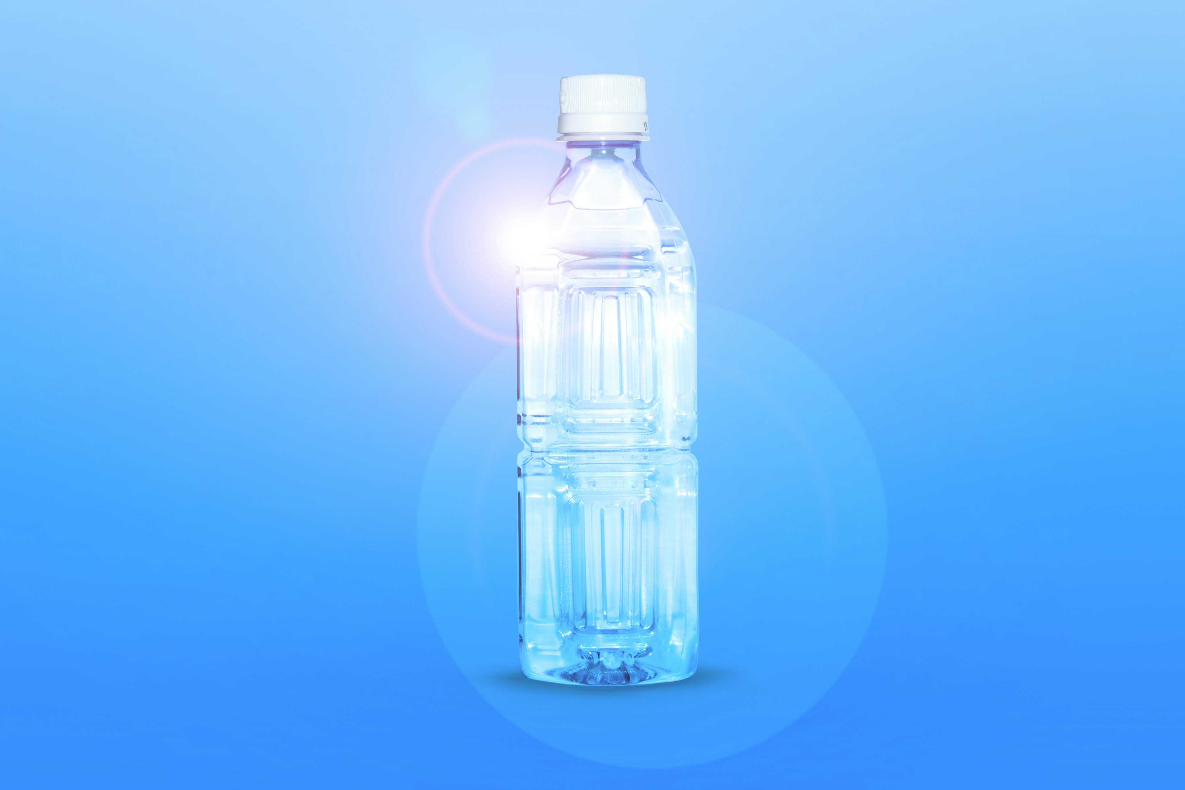 A transparent plastic water bottle glowing against a blue background