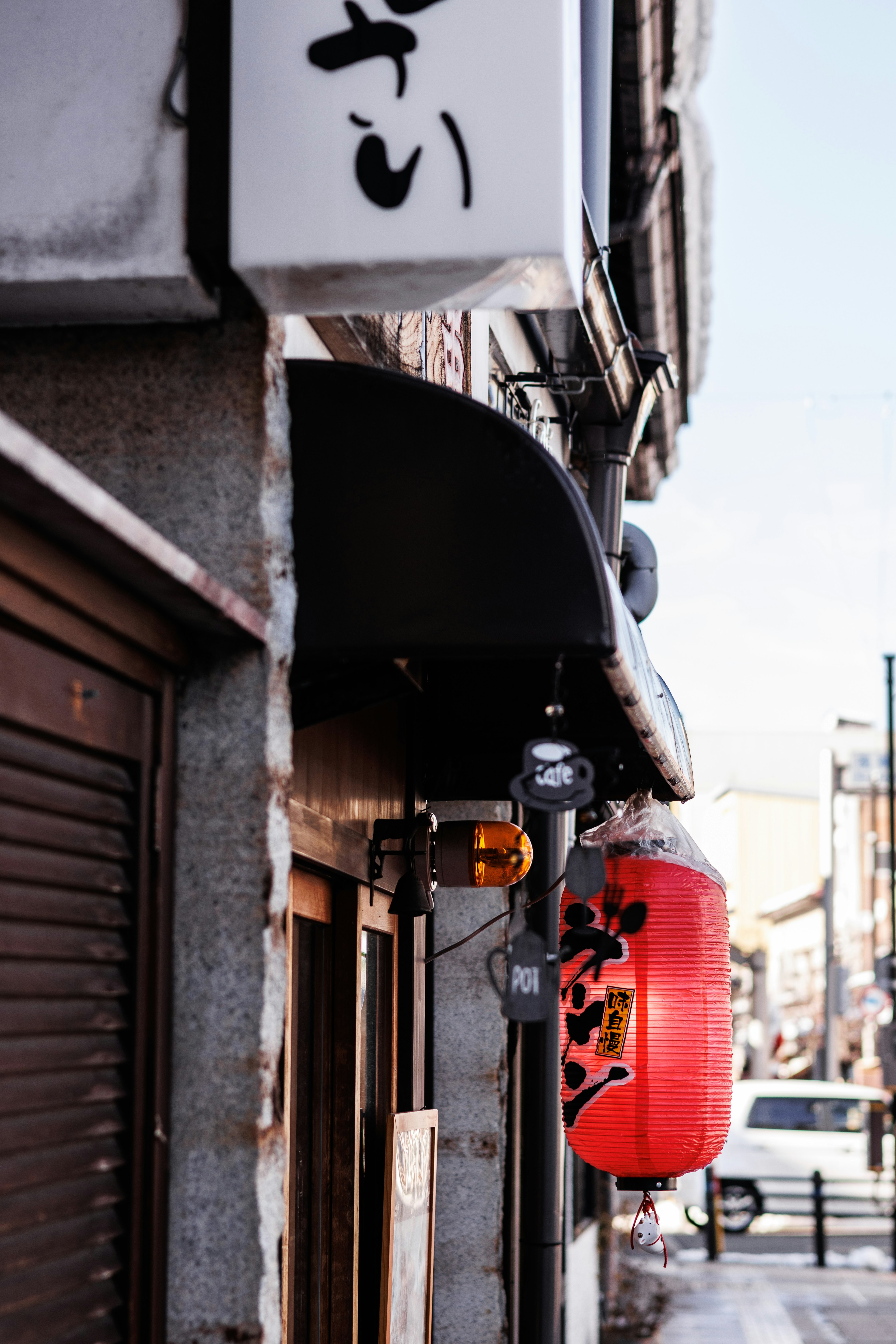 Street corner view featuring a red lantern and a traditional Japanese sign