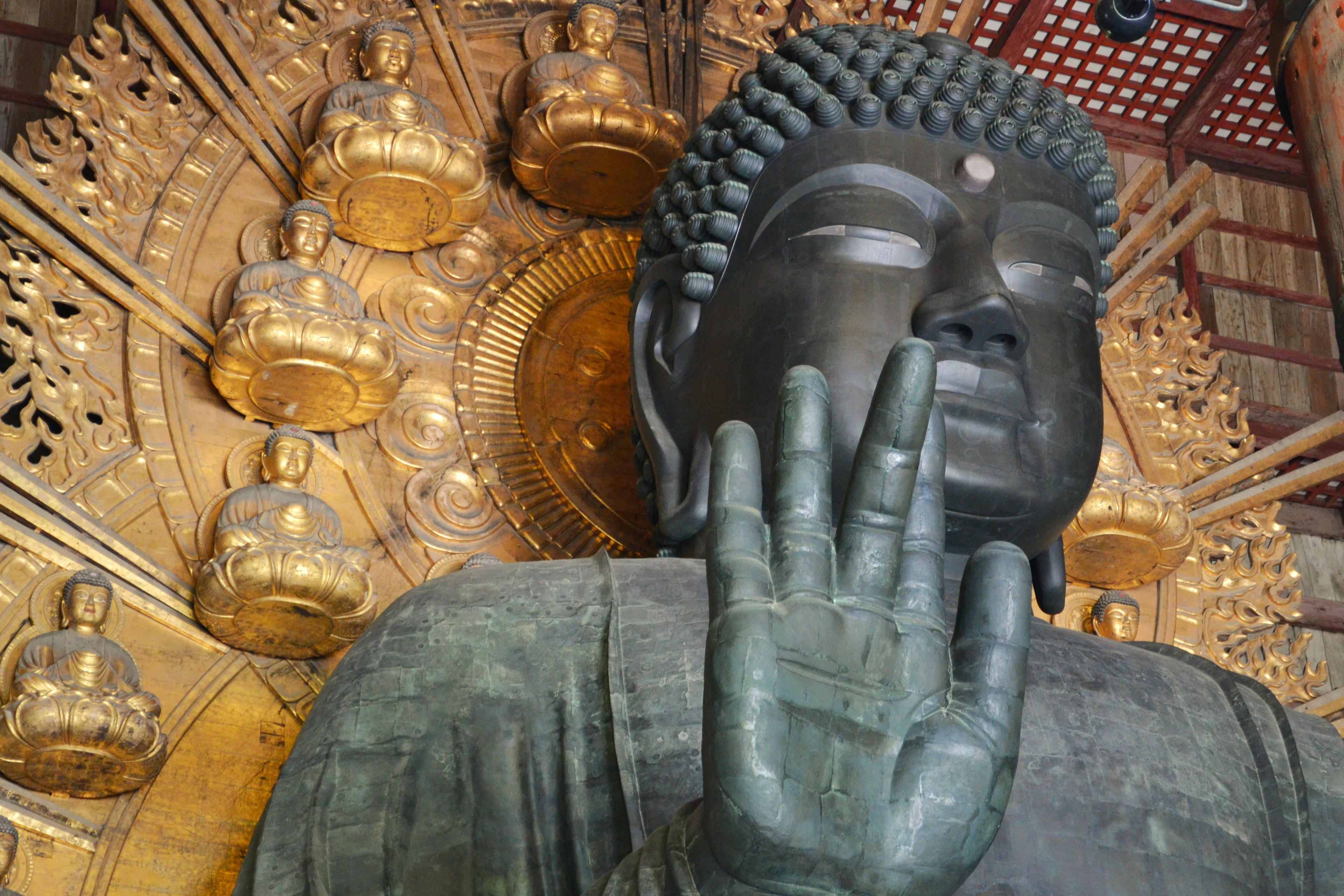 Patung Buddha besar dengan tangan terangkat dan patung emas di latar belakang