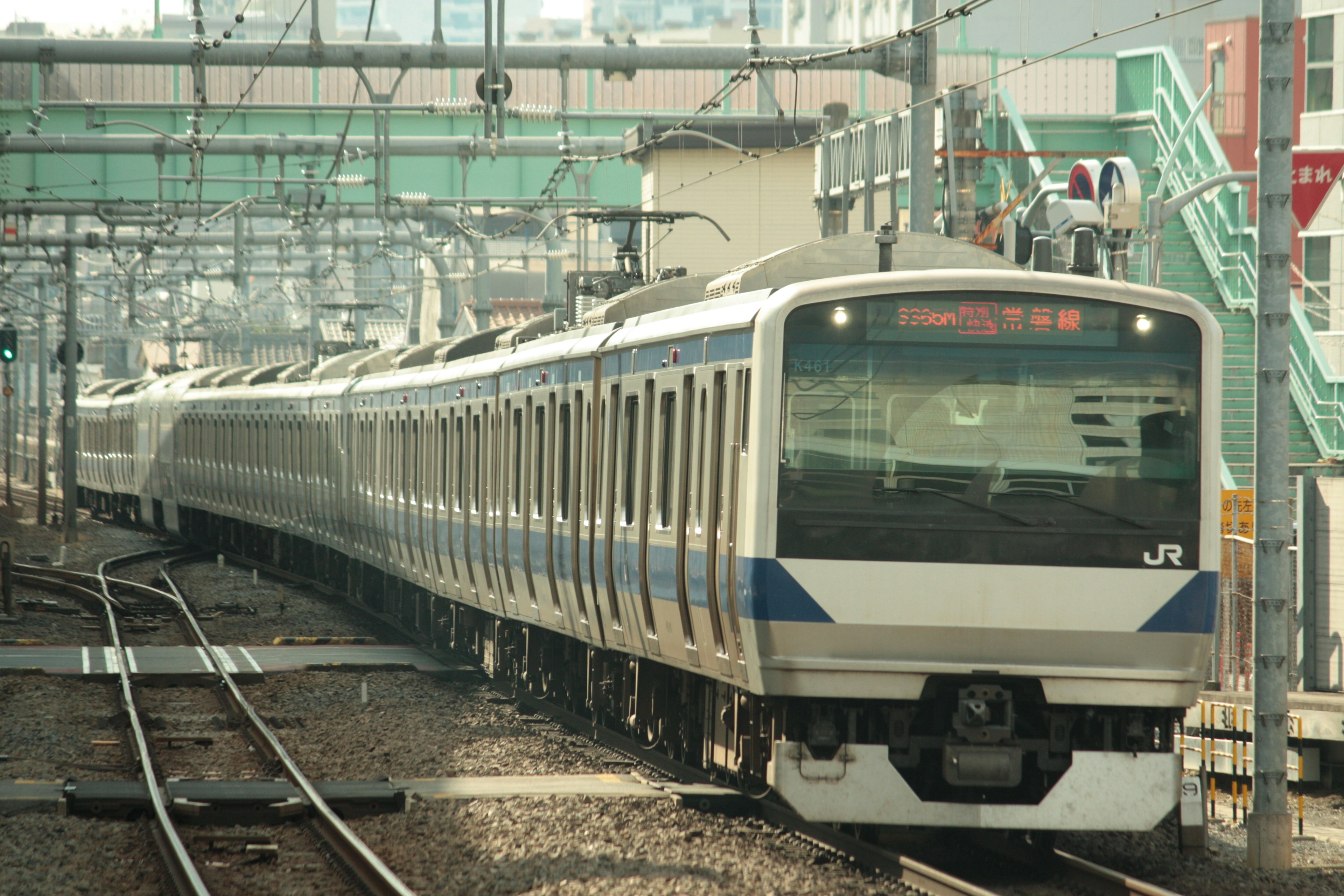 A white-bodied Japanese train traveling on tracks