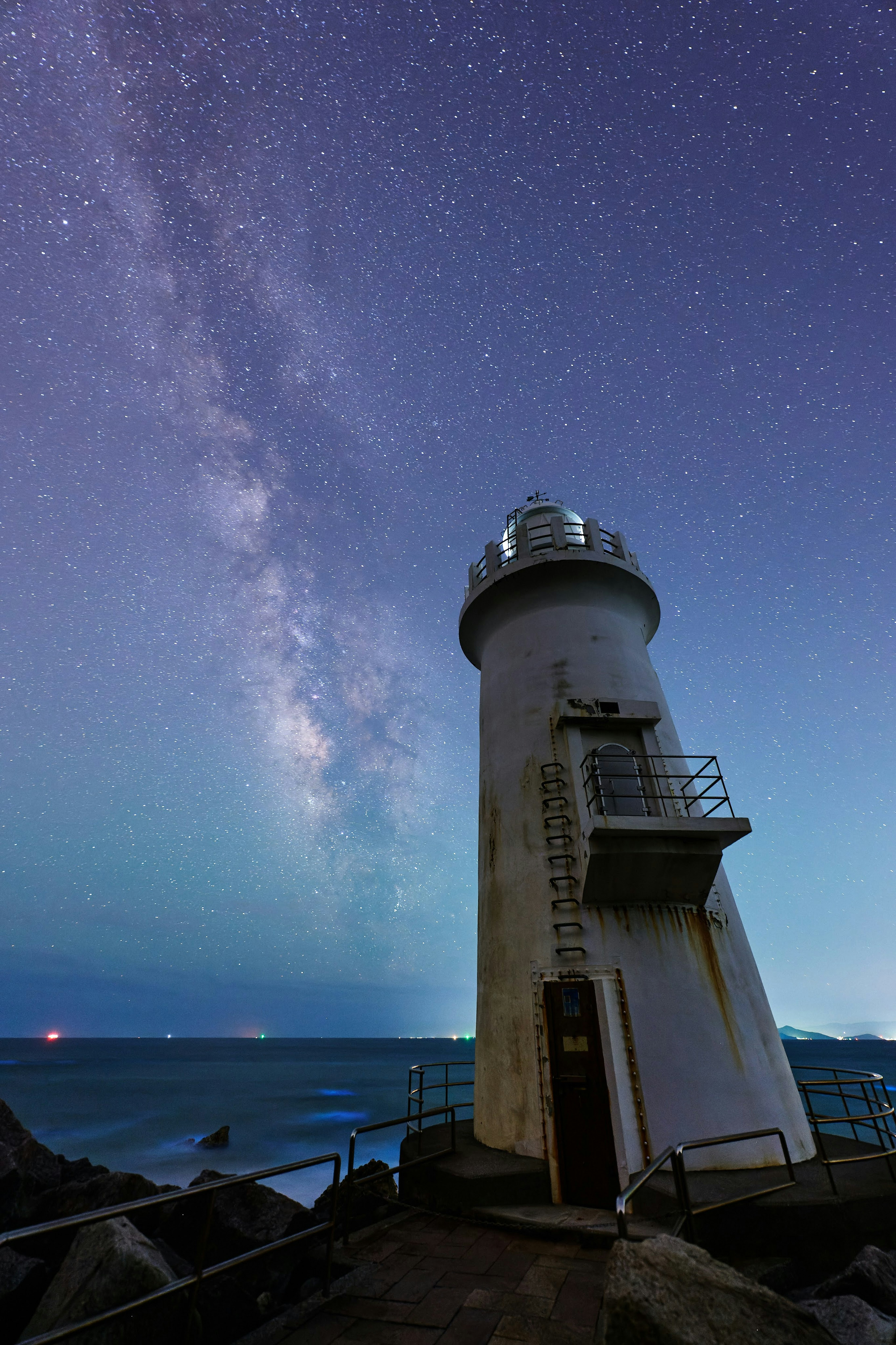 星空の下に立つ灯台と美しい天の川の景色