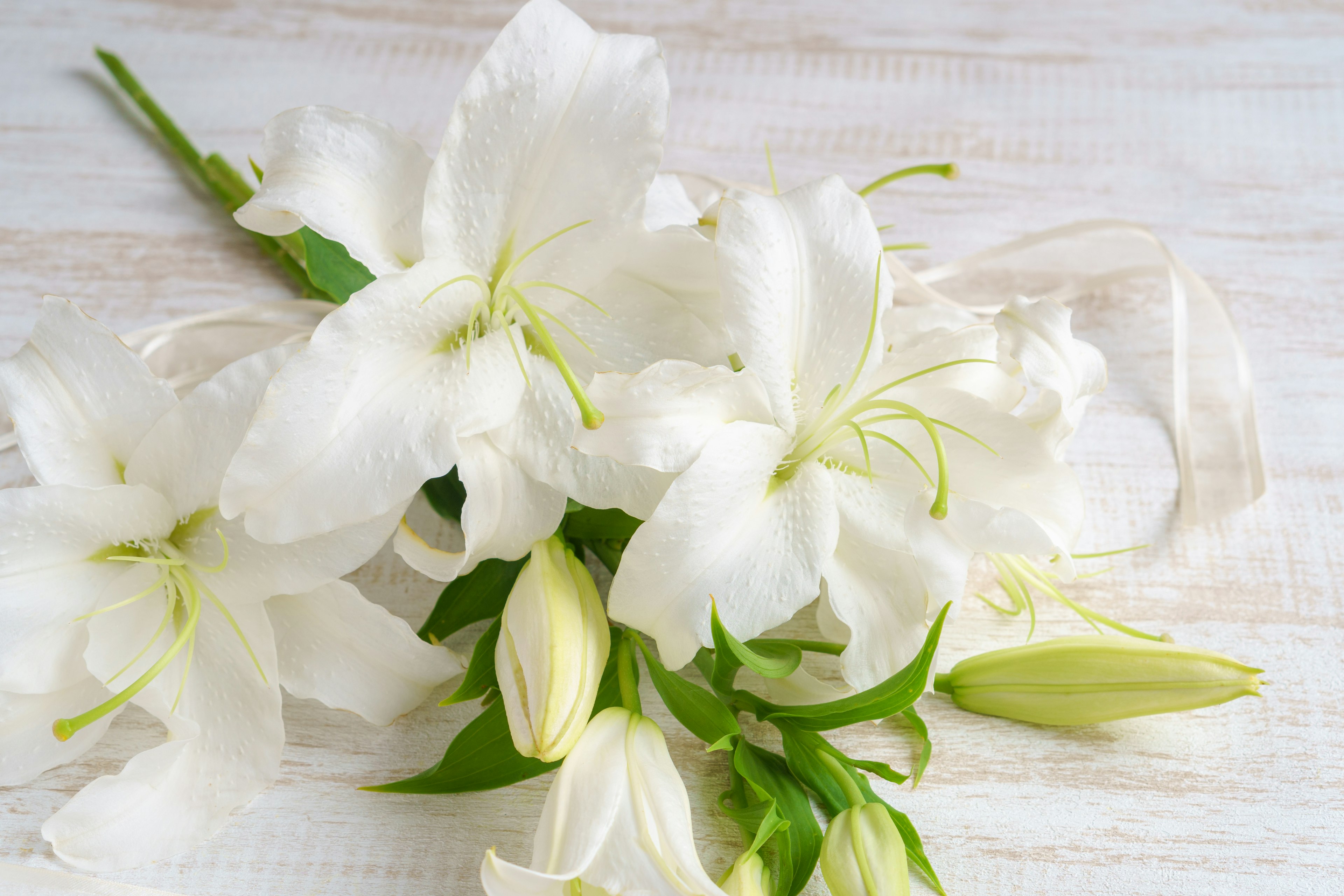 A bouquet of white lilies resting on a wooden table