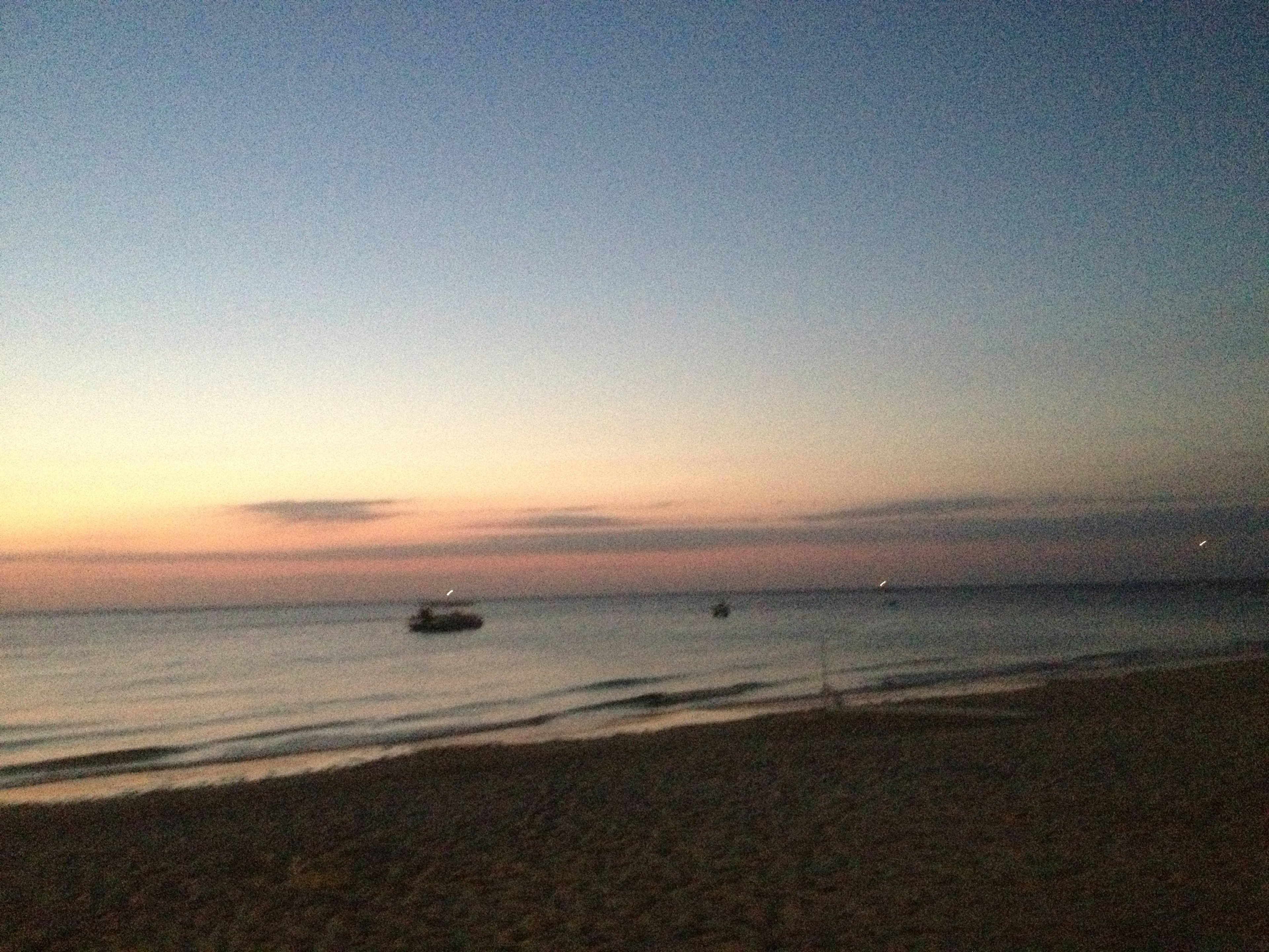 Serene beach at sunset with boats on calm waters