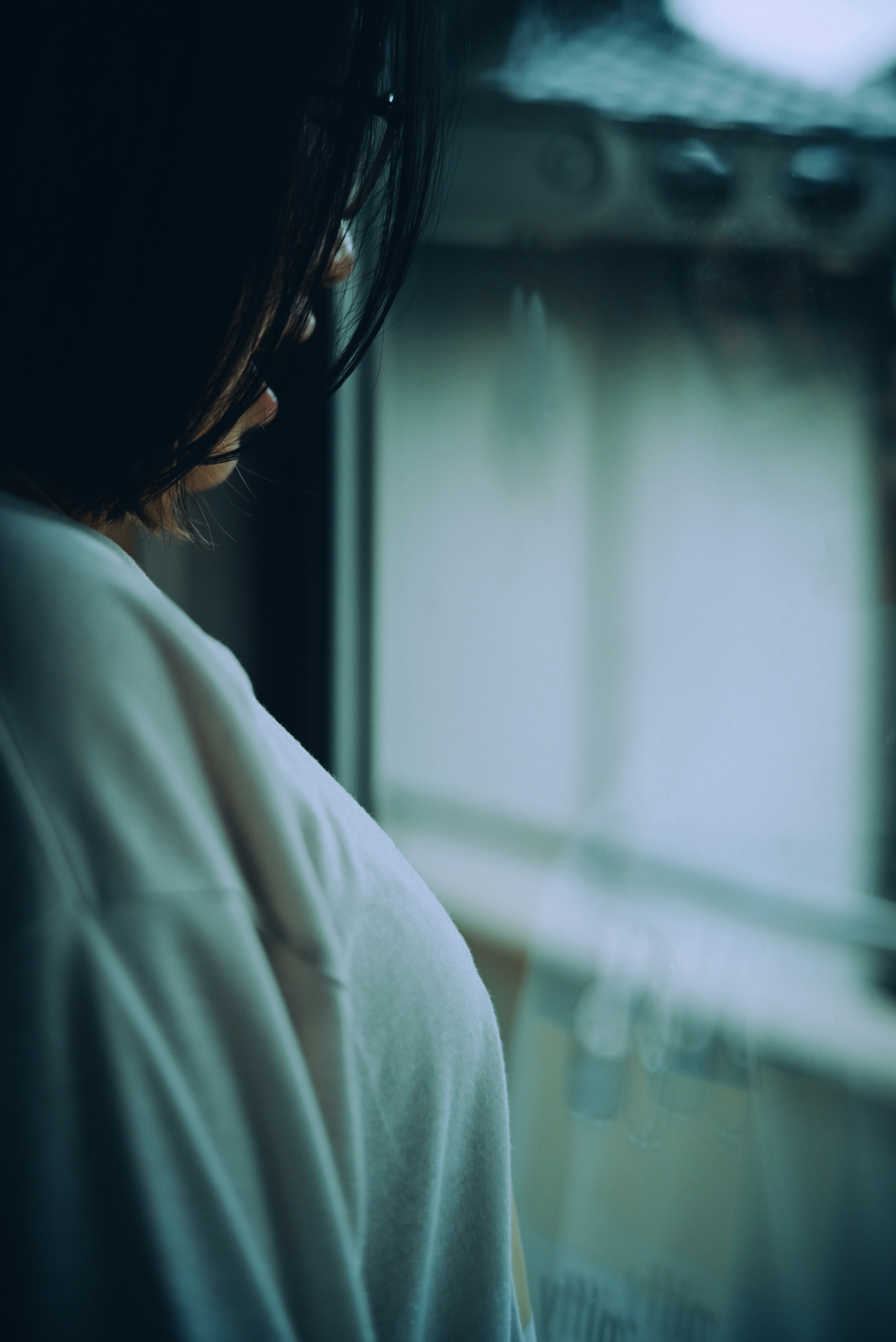 A woman gazing out the window with a soft color palette