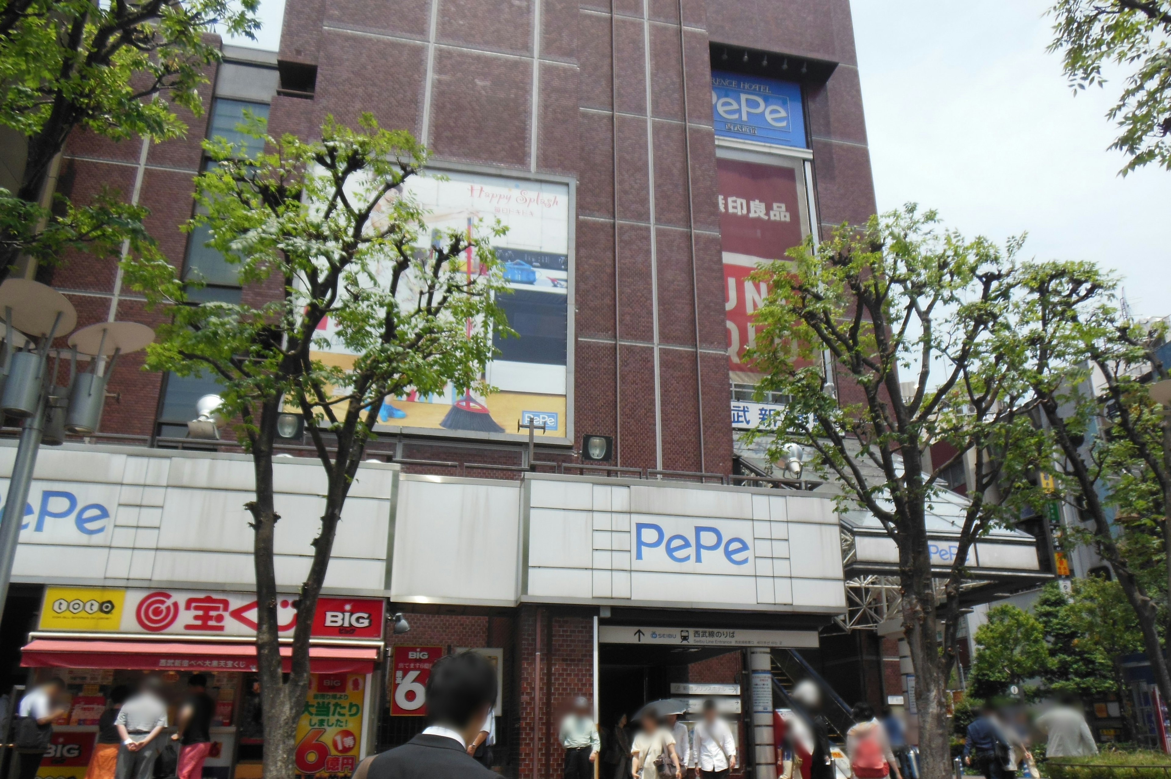 Urban scene with a reddish-brown building and green trees featuring a prominent PePe sign