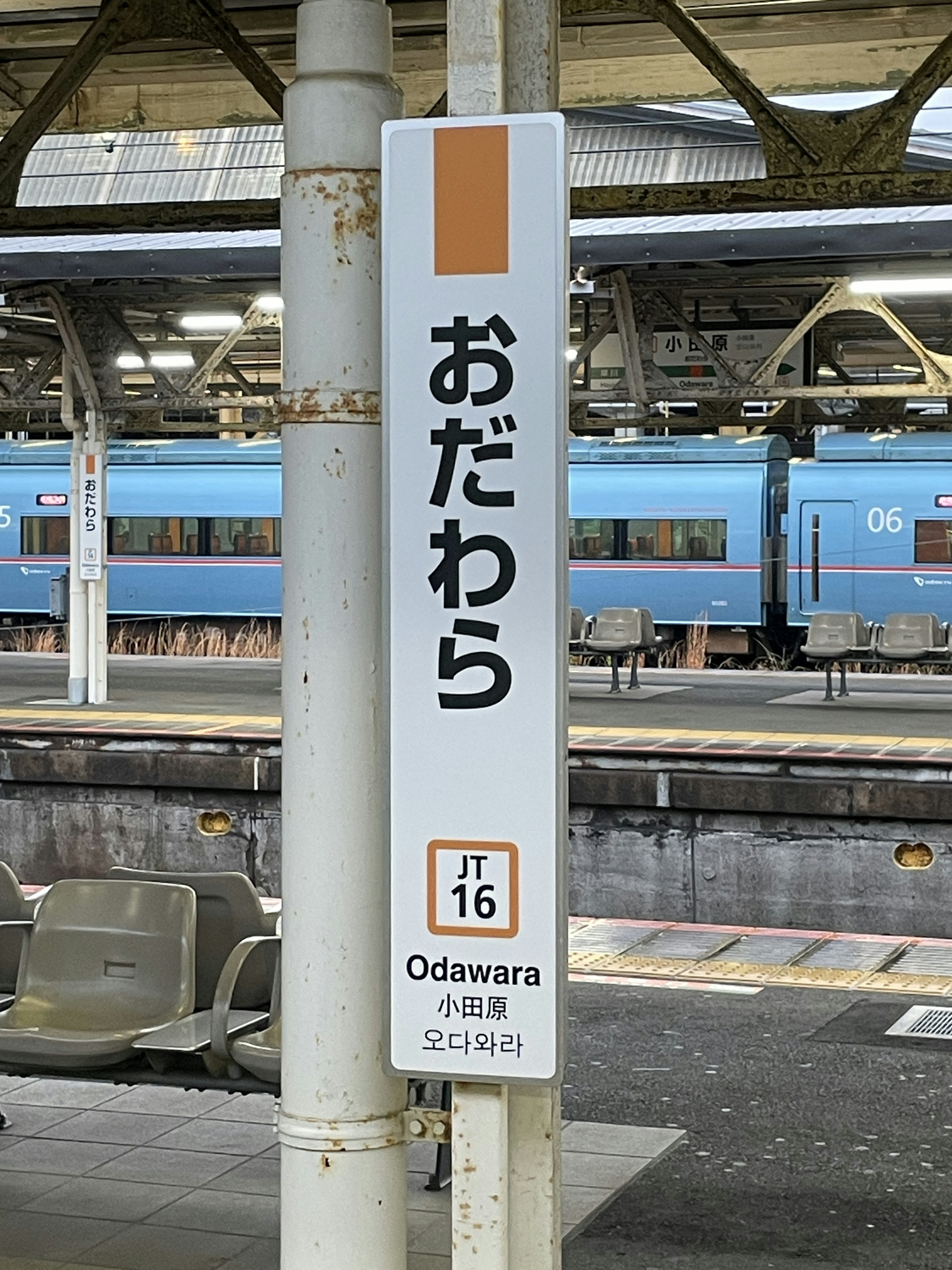 小田原駅の看板と青い電車が見える駅のプラットフォーム