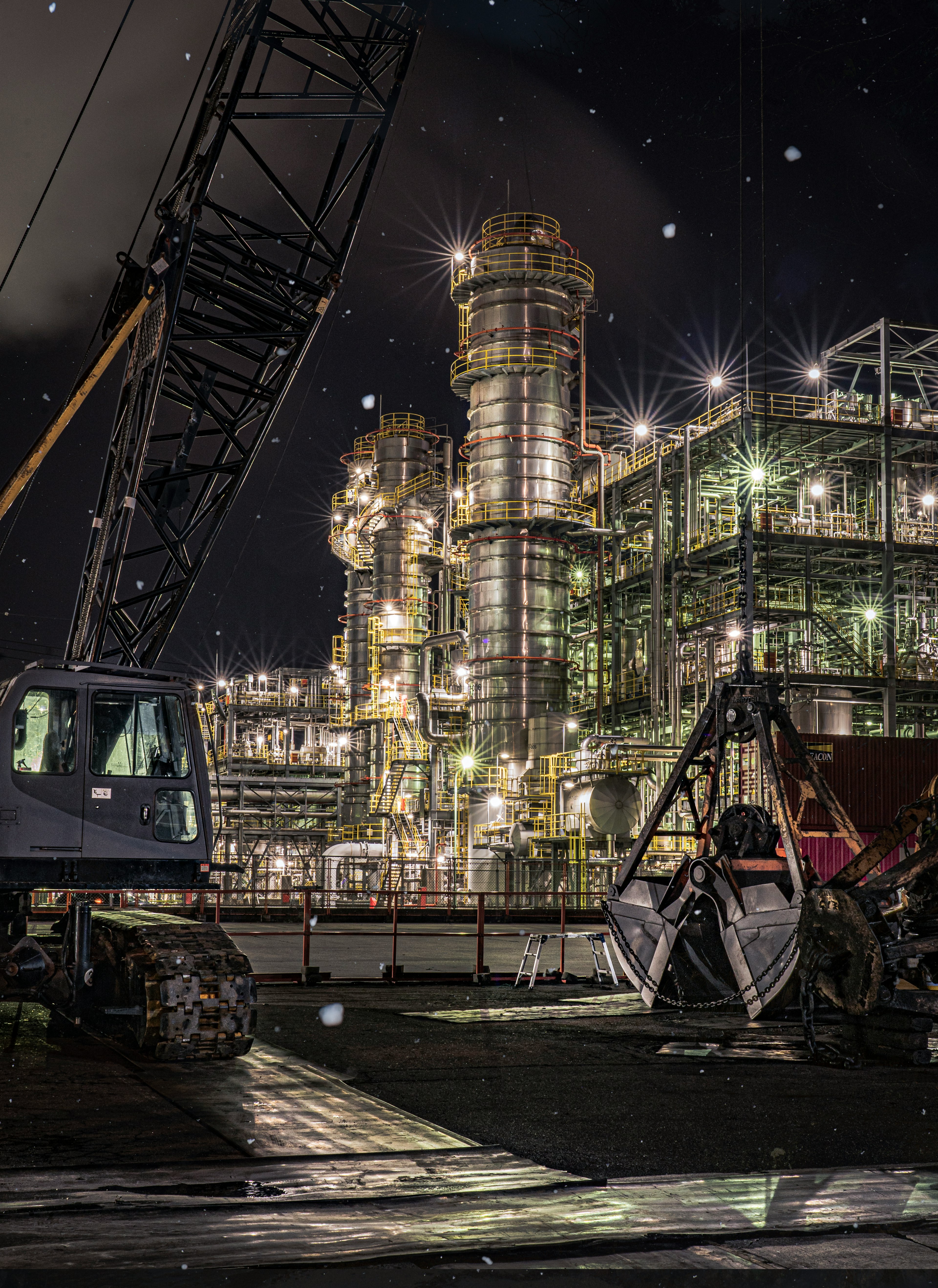 Usine industrielle nocturne avec structures illuminées et grue