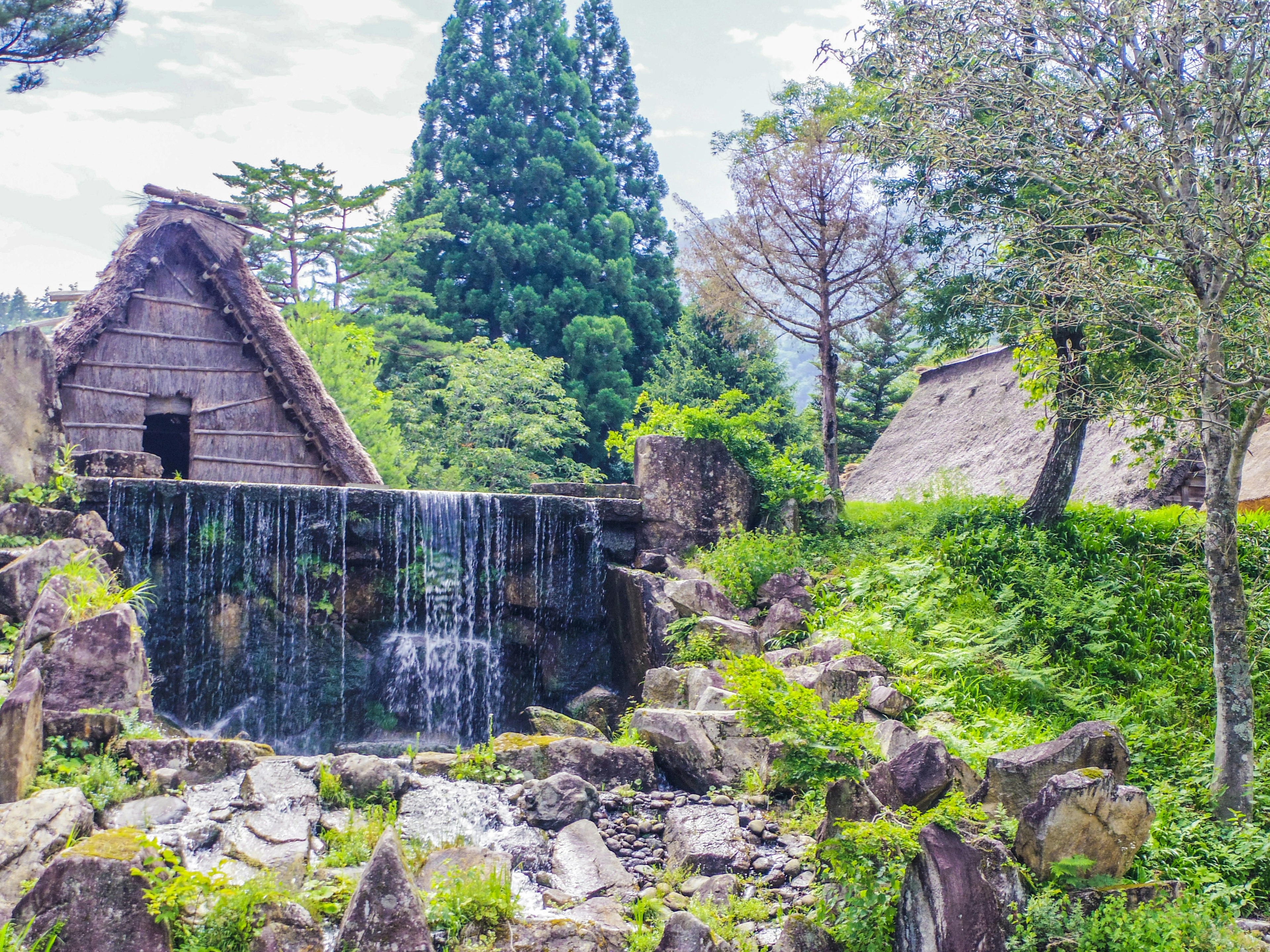 Maisons traditionnelles à toit de chaume dans un beau paysage rural japonais avec une petite cascade