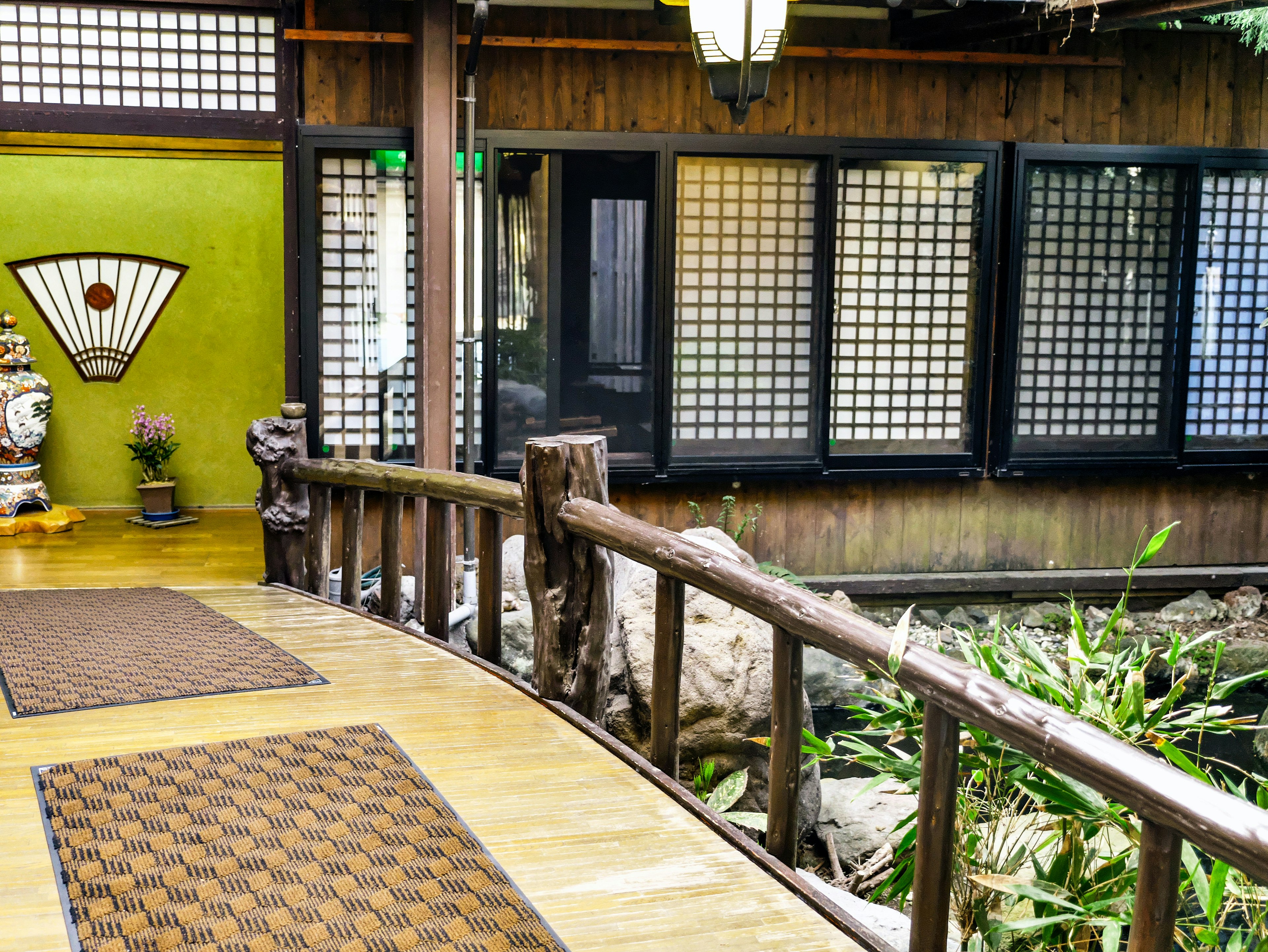 Interior japonés tradicional con un puente de madera y una pared verde