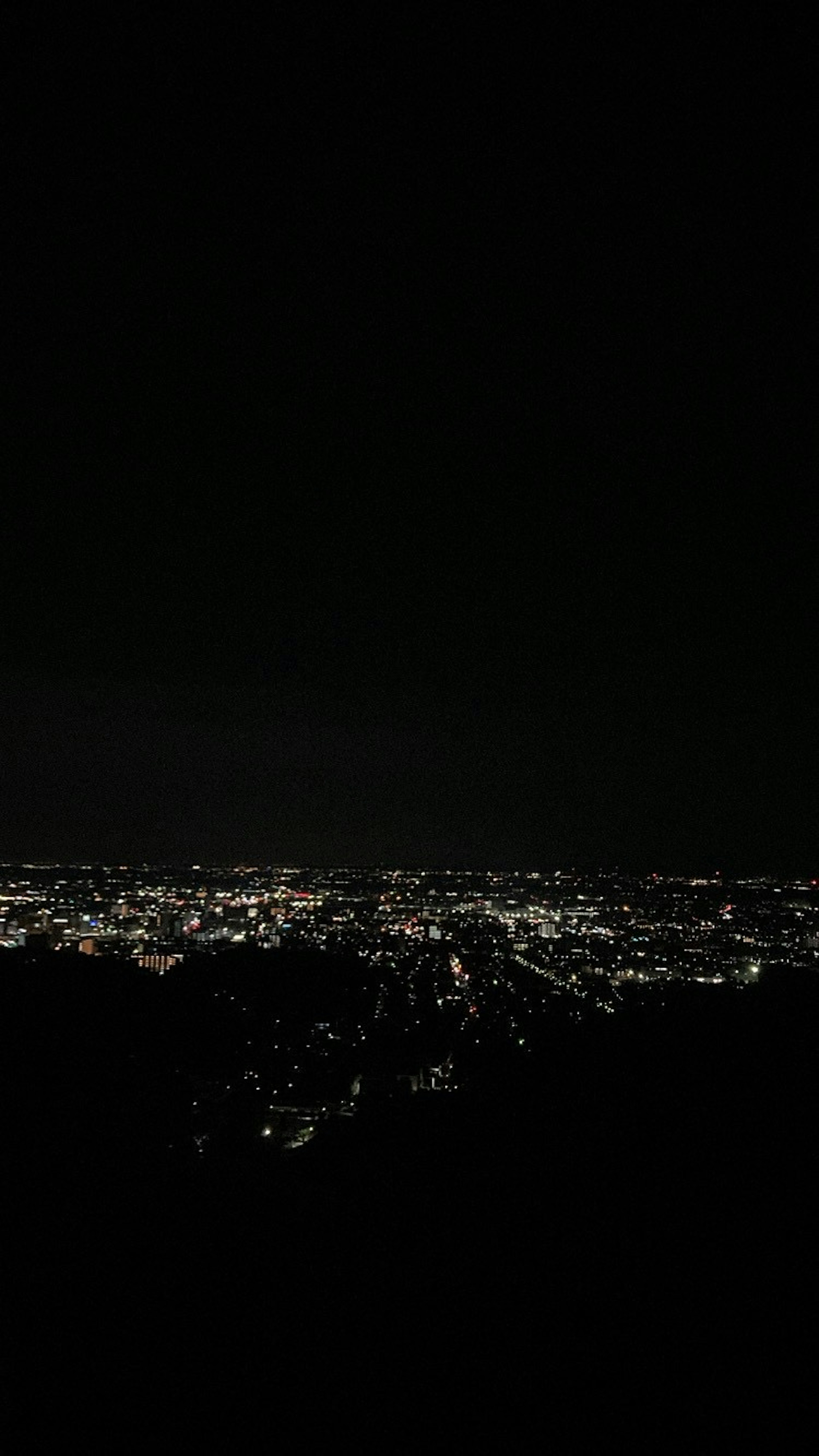 夜の都市の光が広がる風景暗い空と明るい街の明かり