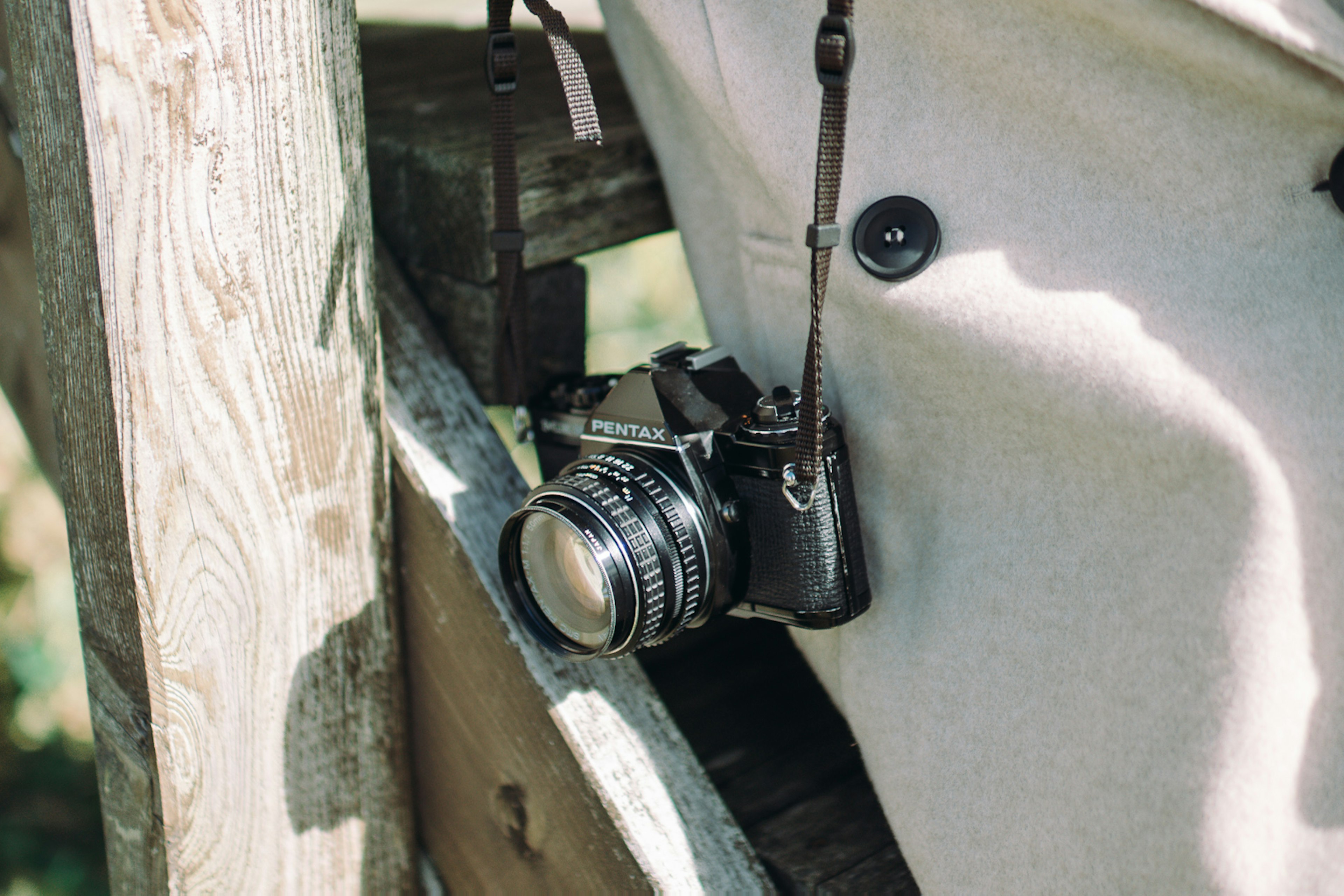 A camera hanging on a wooden fence