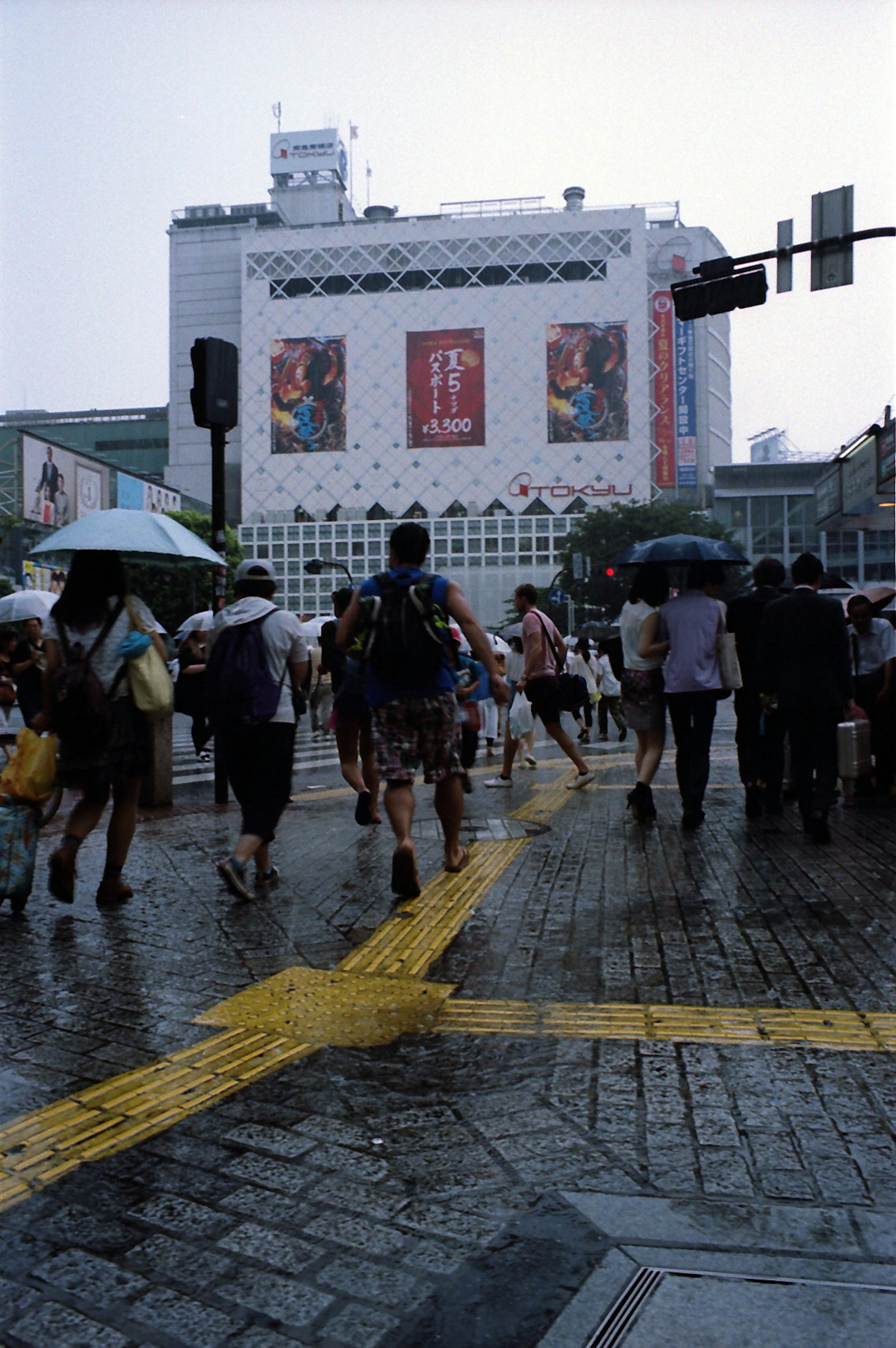 雨の中で傘を持った人々が行き交う繁華街の交差点