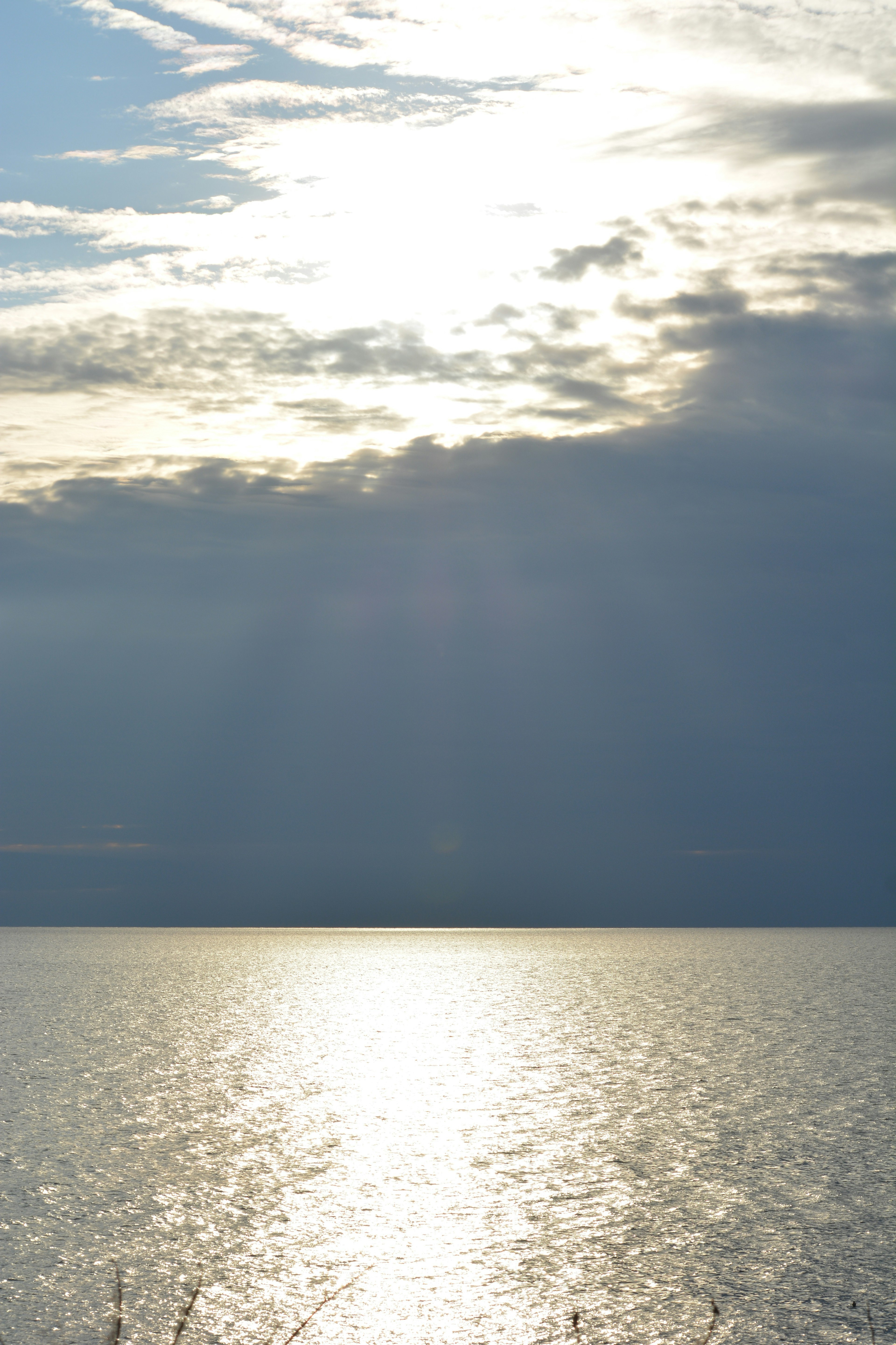 Vista serena de la luz del sol reflejándose en el agua tranquila con nubes