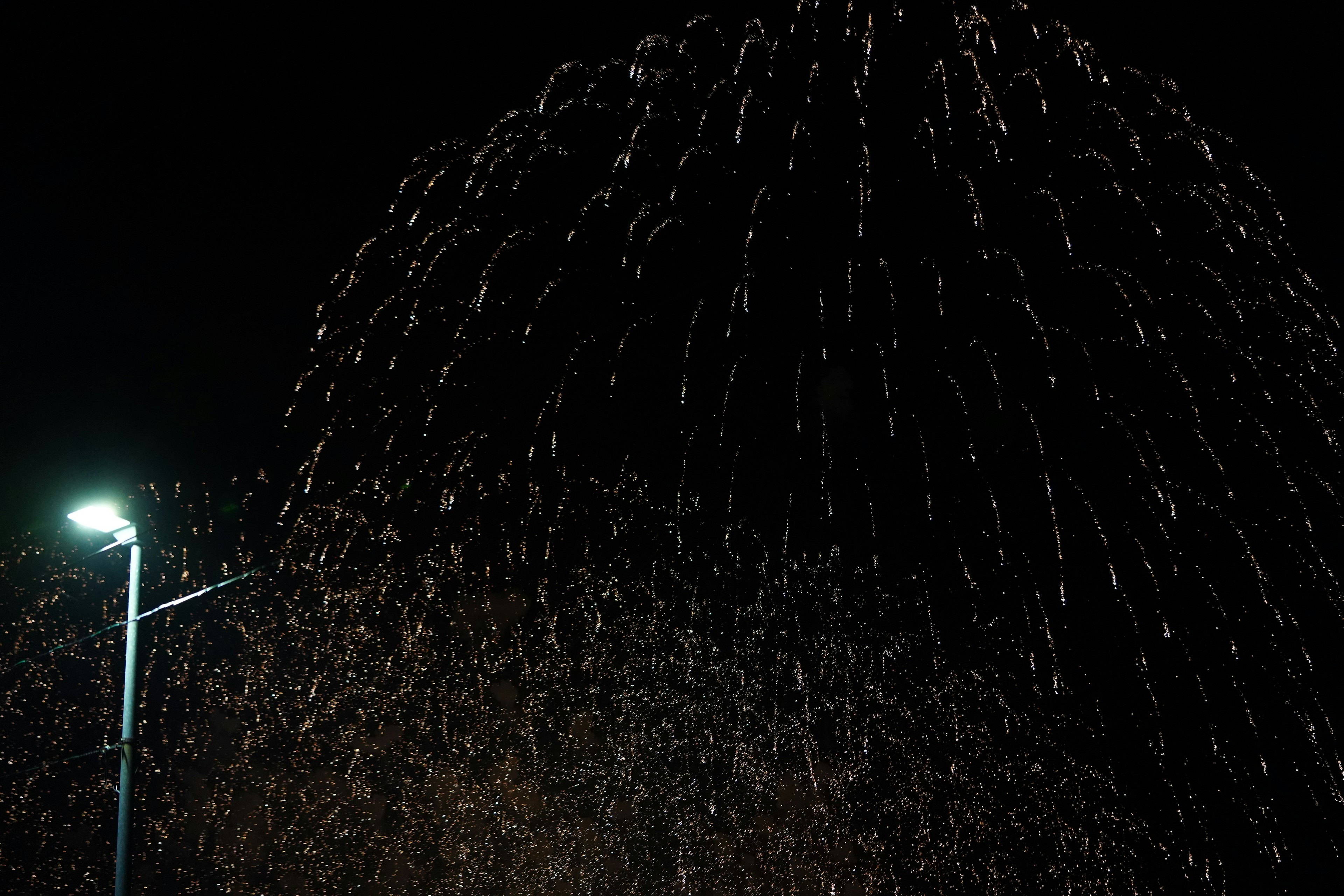 Spectacle de feux d'artifice dans le ciel nocturne avec un lampadaire