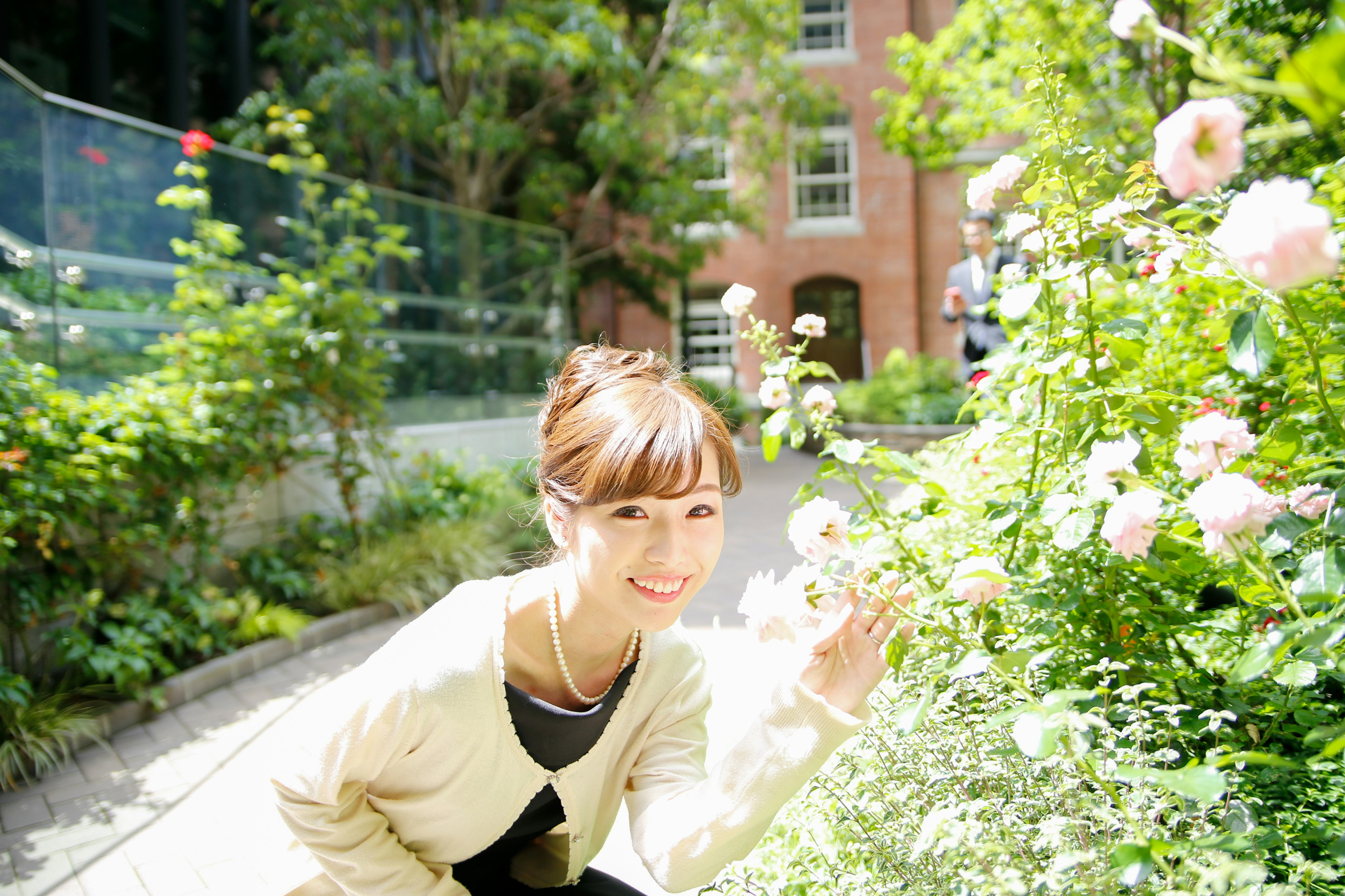 女性が花を手に持ち微笑む庭の風景