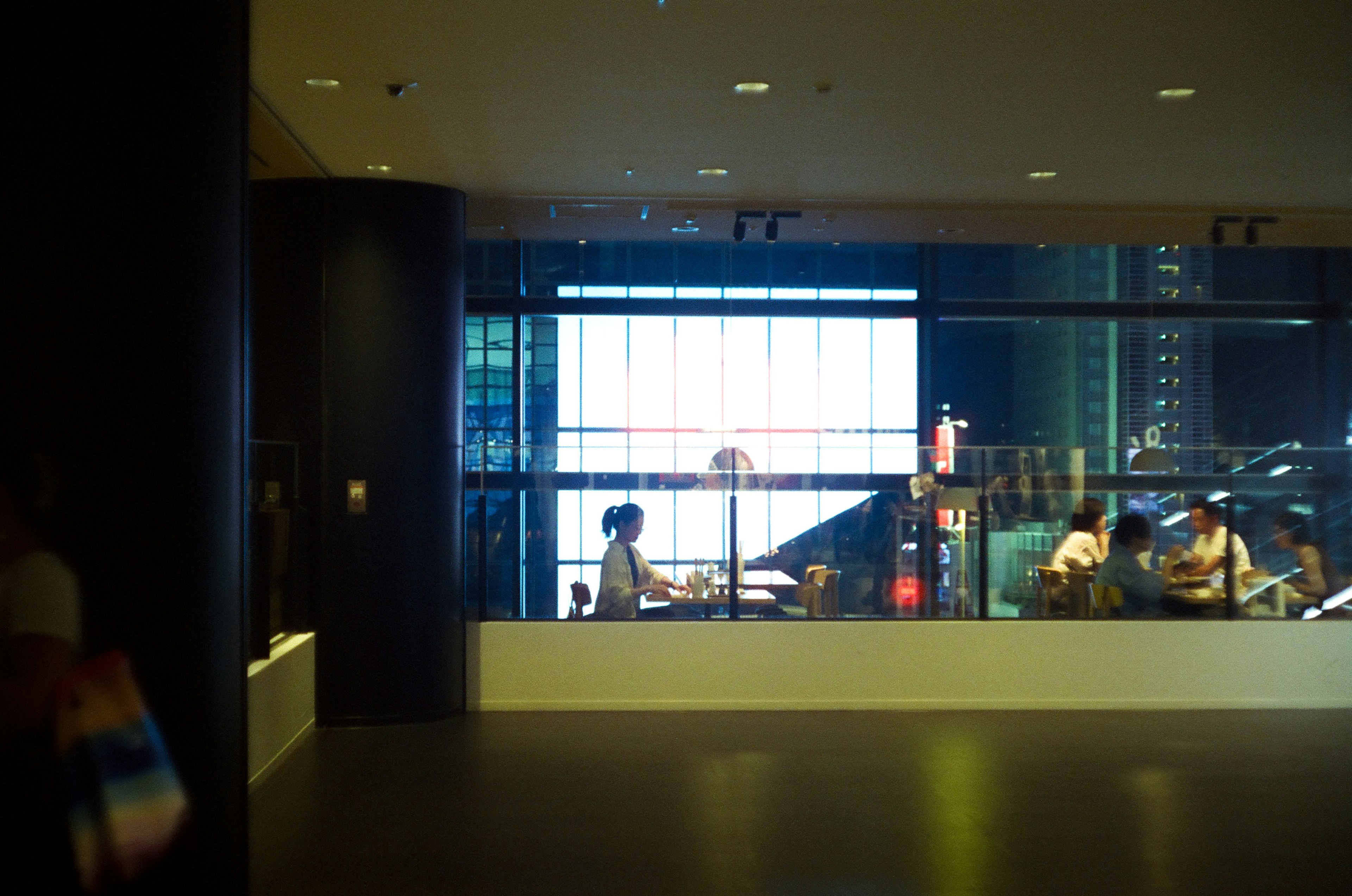 Image featuring people in a modern interior space visible through a large window